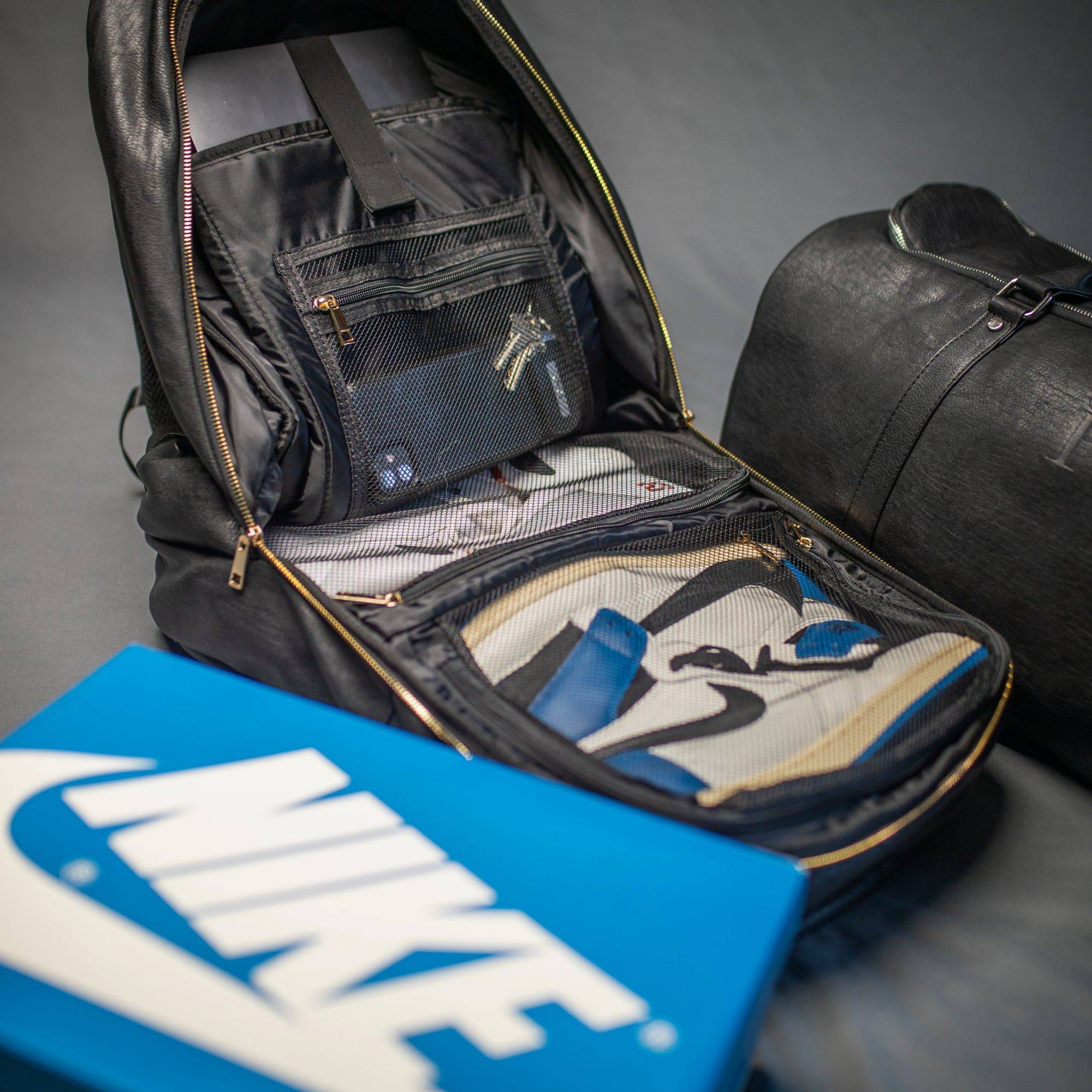 Open black backpack with a Nike box on a gray background