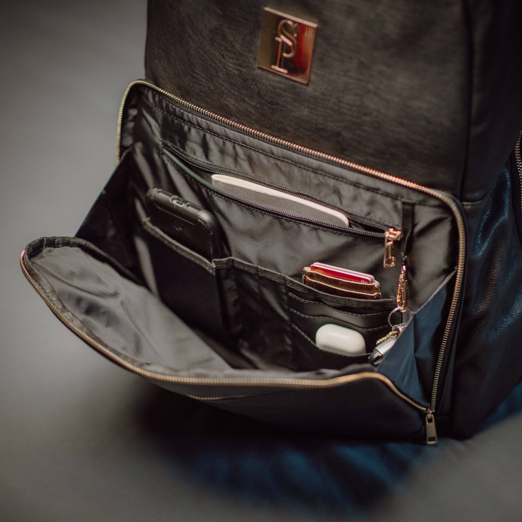 Open black backpack with organized compartments on a gray background
