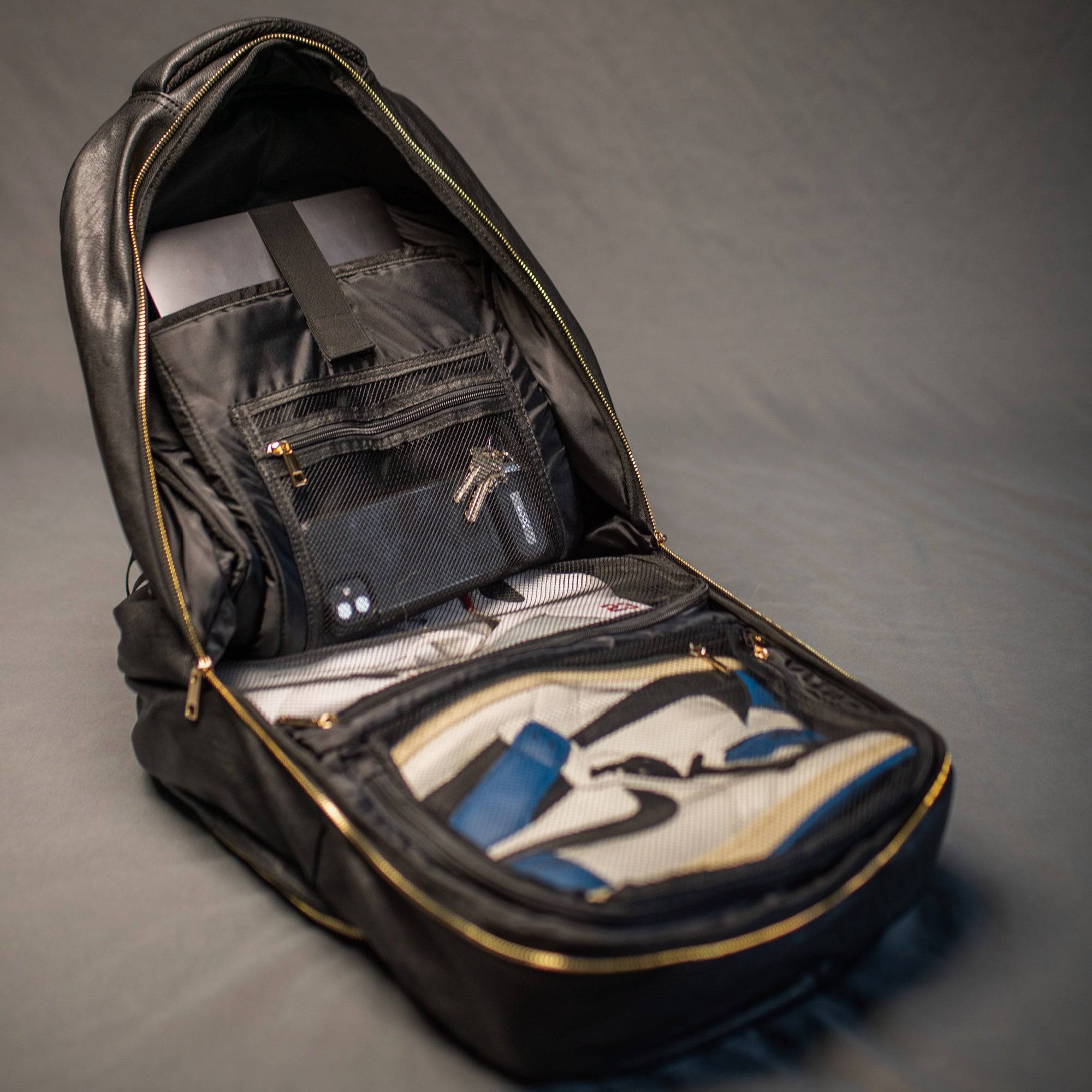 Open black backpack with compartments on a gray background