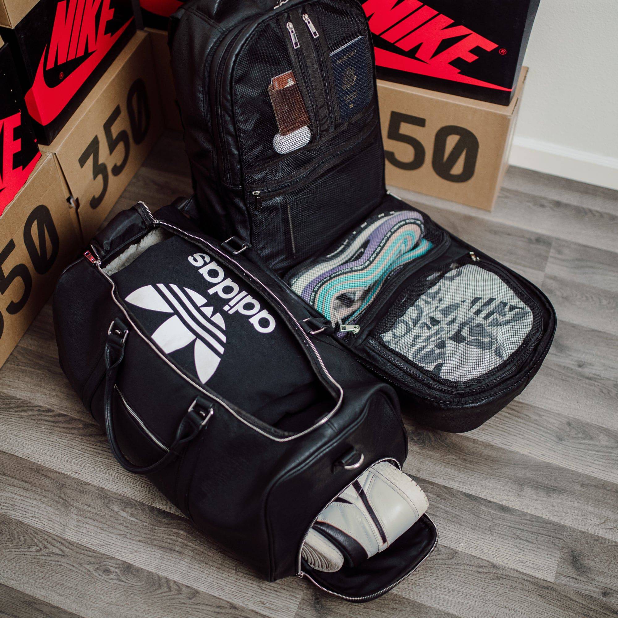 Black Adidas bag with sneakers on a wooden floor with Nike boxes in the background