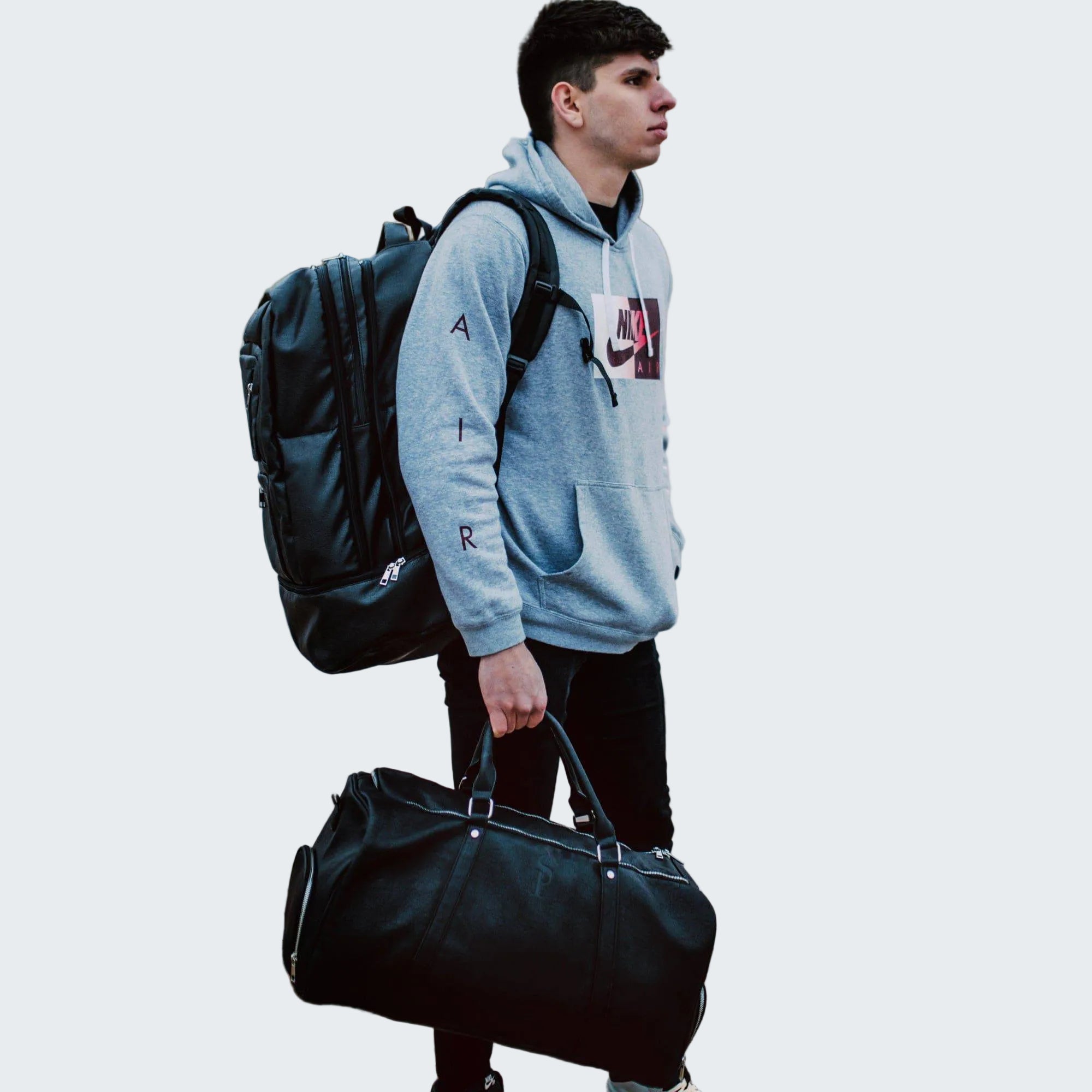 Person with a backpack and duffel bag on a city street