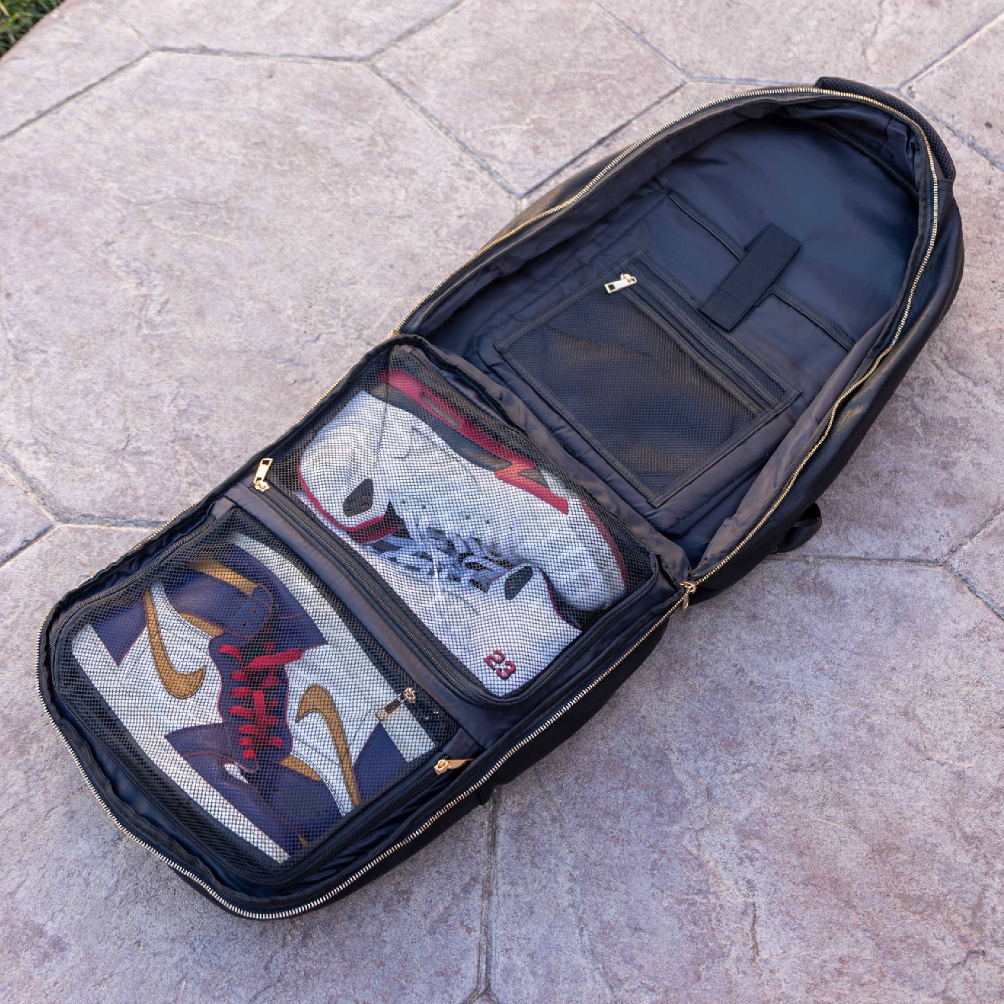 Open backpack with two pairs of sneakers inside on a stone pavement.