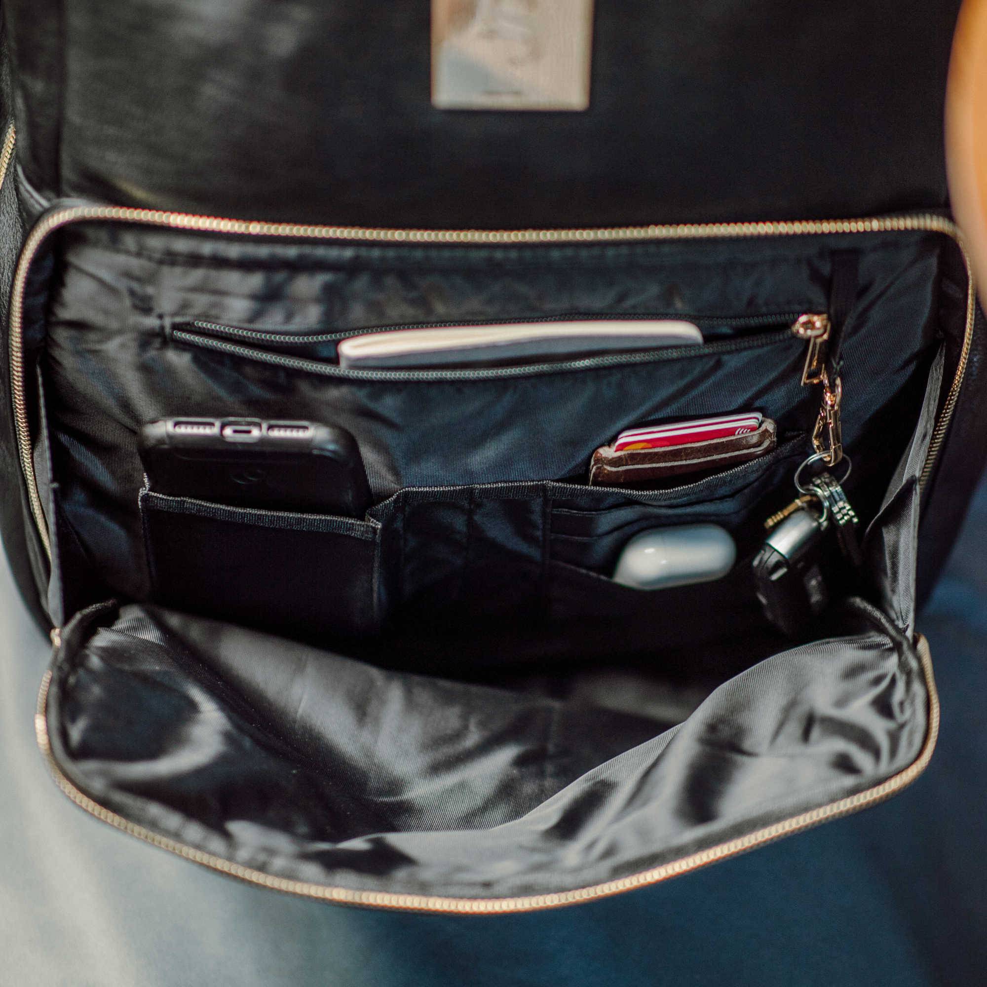 Open black backpack with various items inside