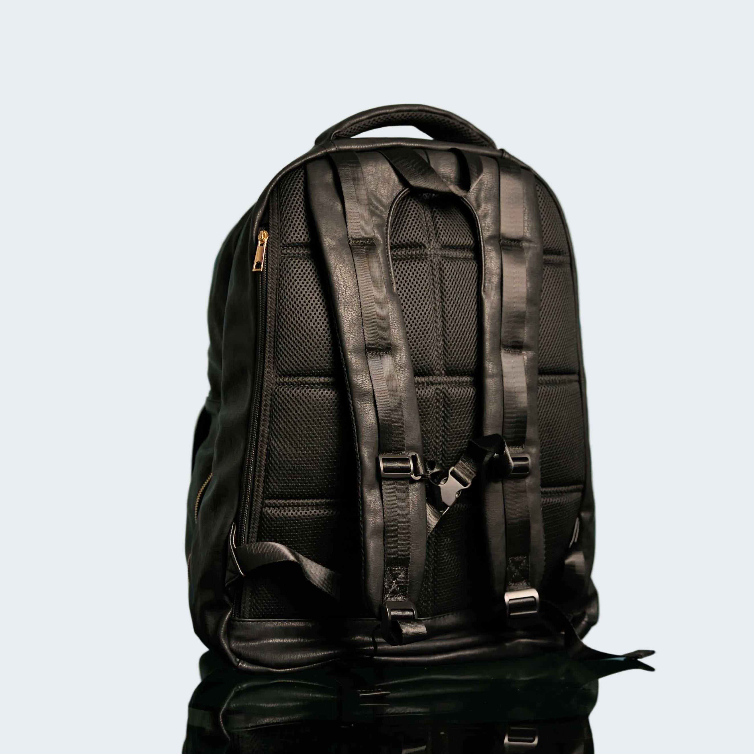 Black backpack on a reflective surface with a light blue patterned background