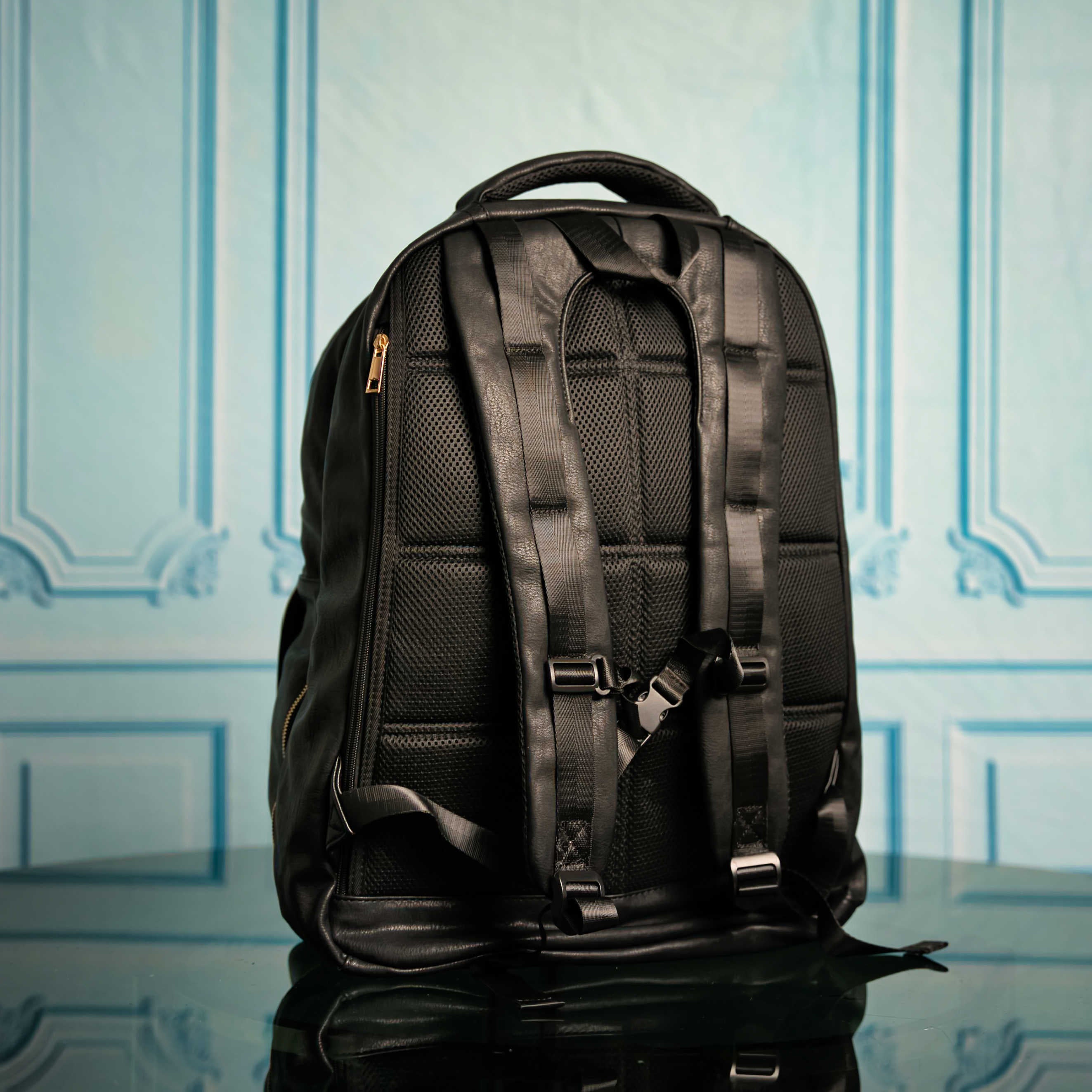 Black backpack on a reflective surface with a light blue patterned background