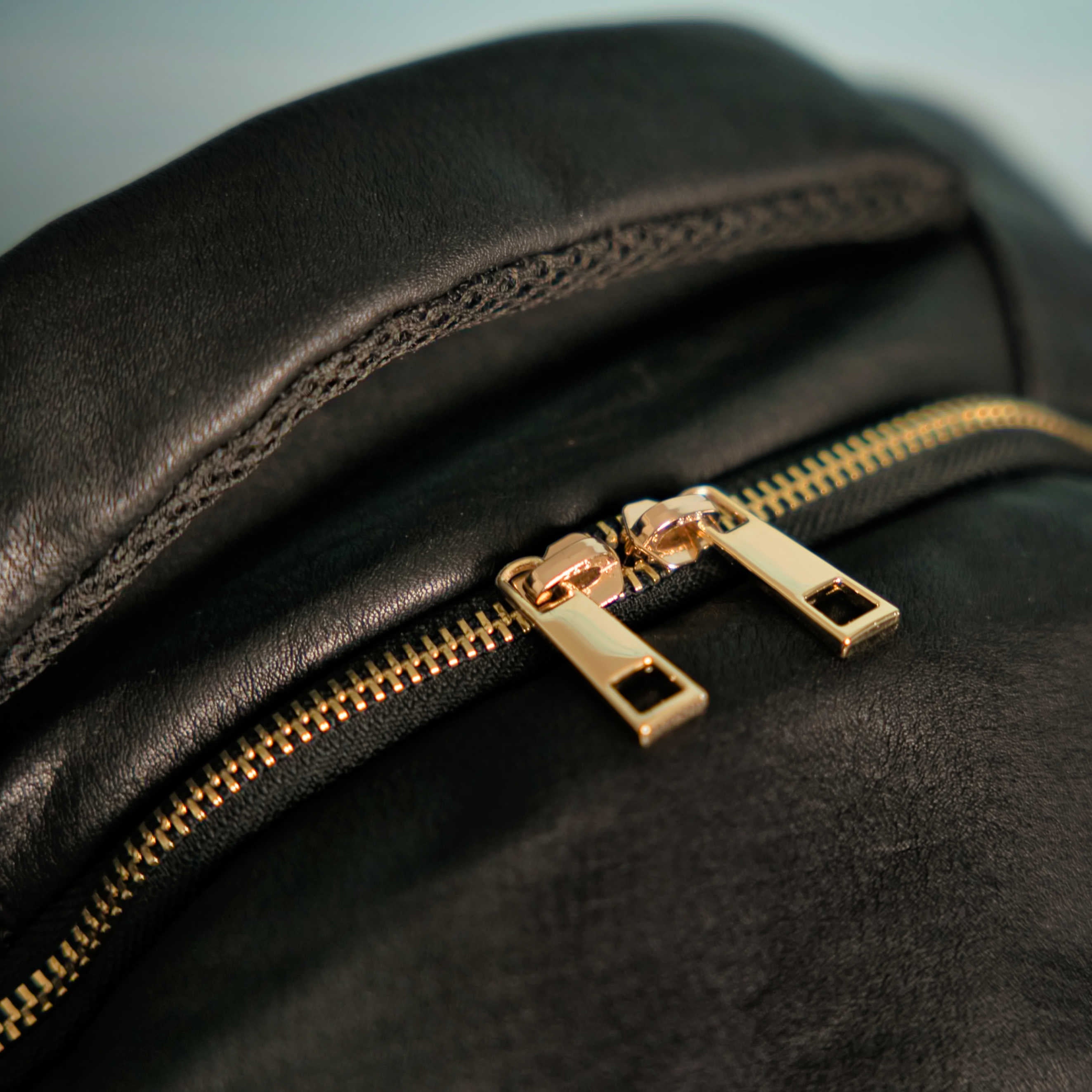 Close-up of a black leather bag with a gold zipper