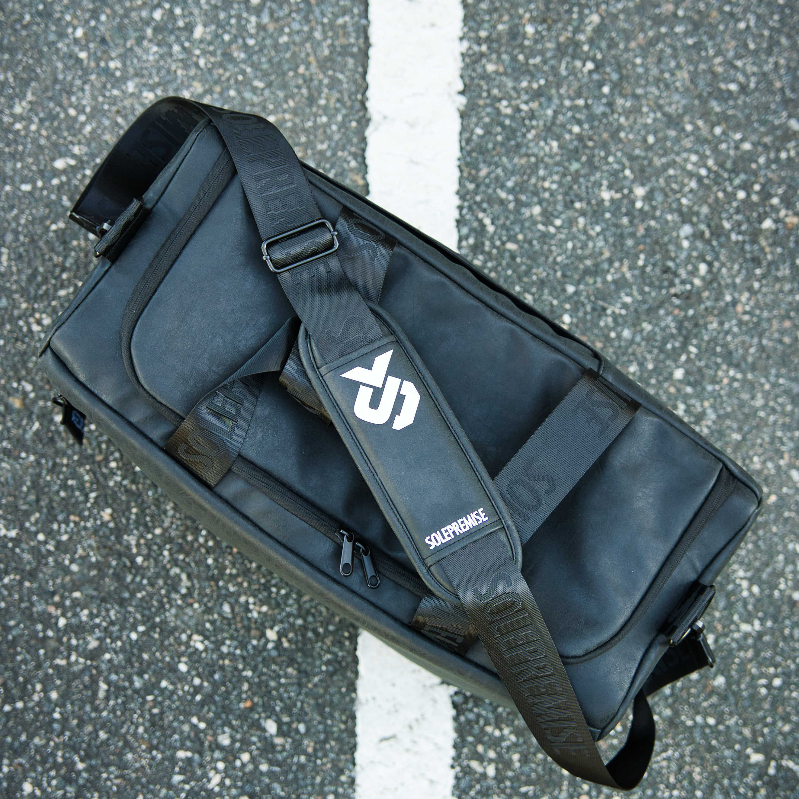 Black bag with a brand logo on a gray asphalt surface
