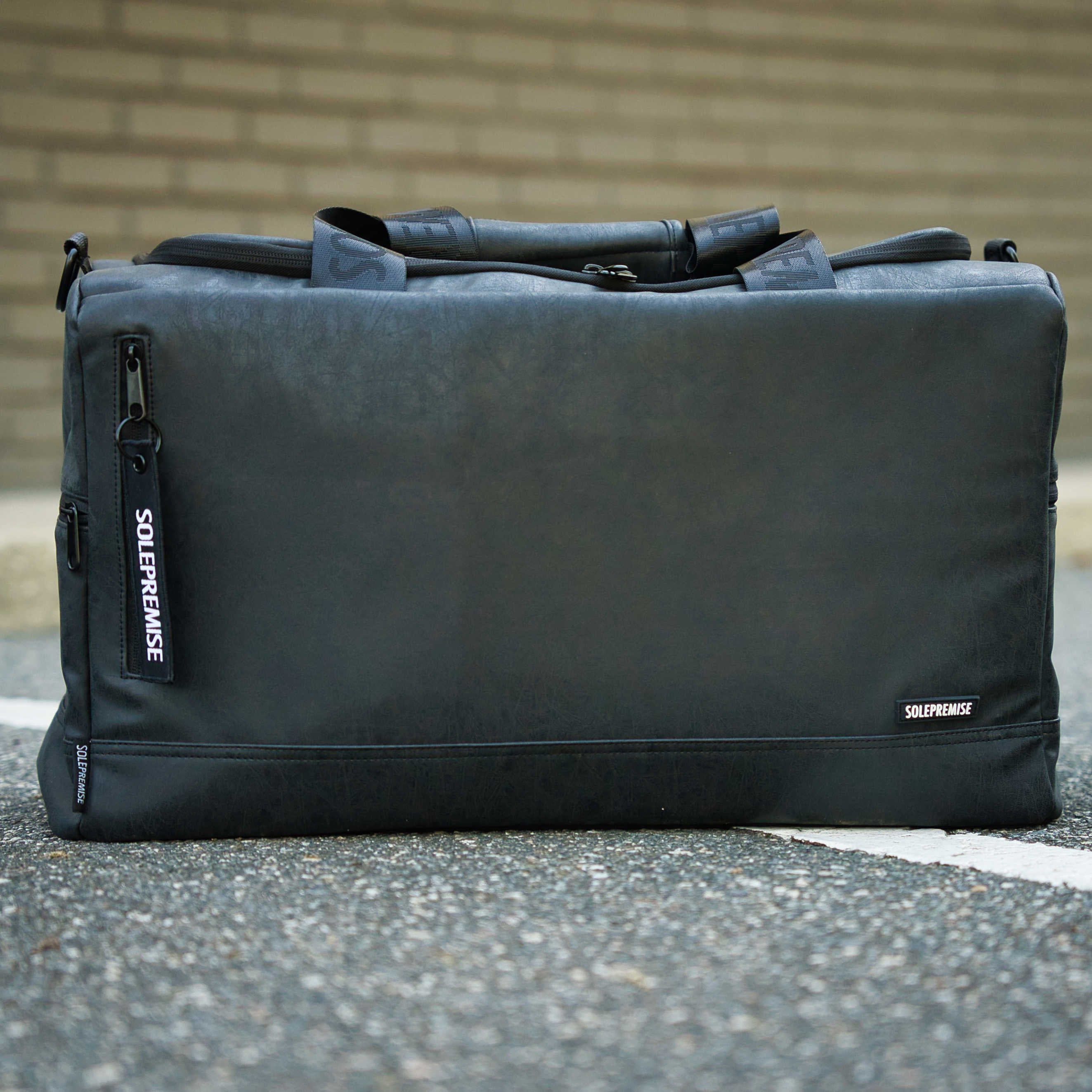 Black duffel bag with 'Solepremise' branding on a concrete surface.