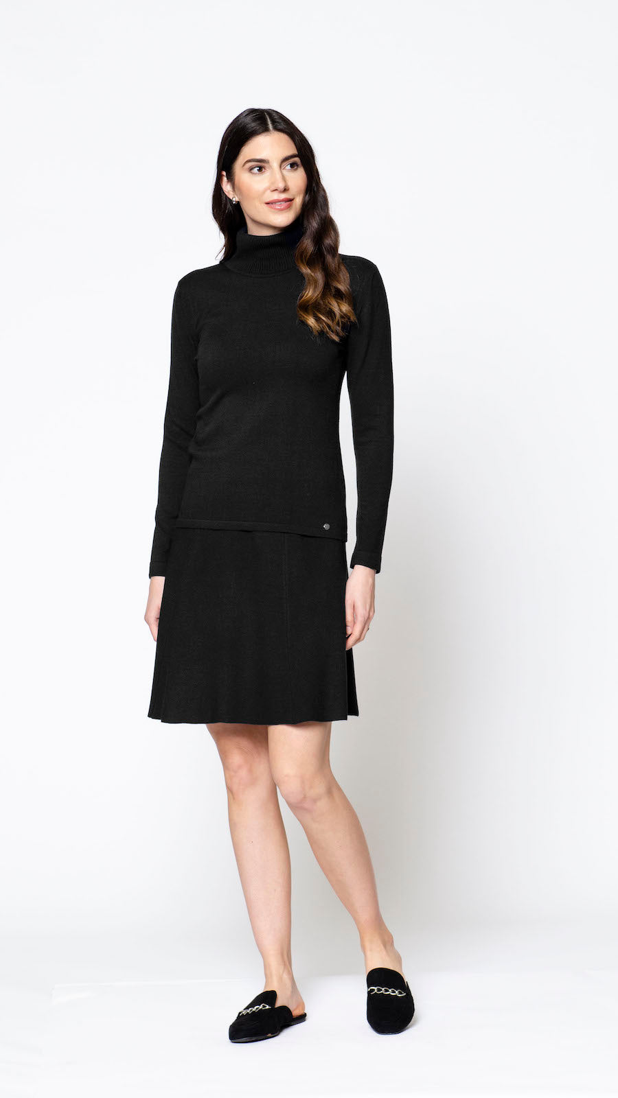 Woman wearing a black outfit with a turtleneck and skirt on a white background