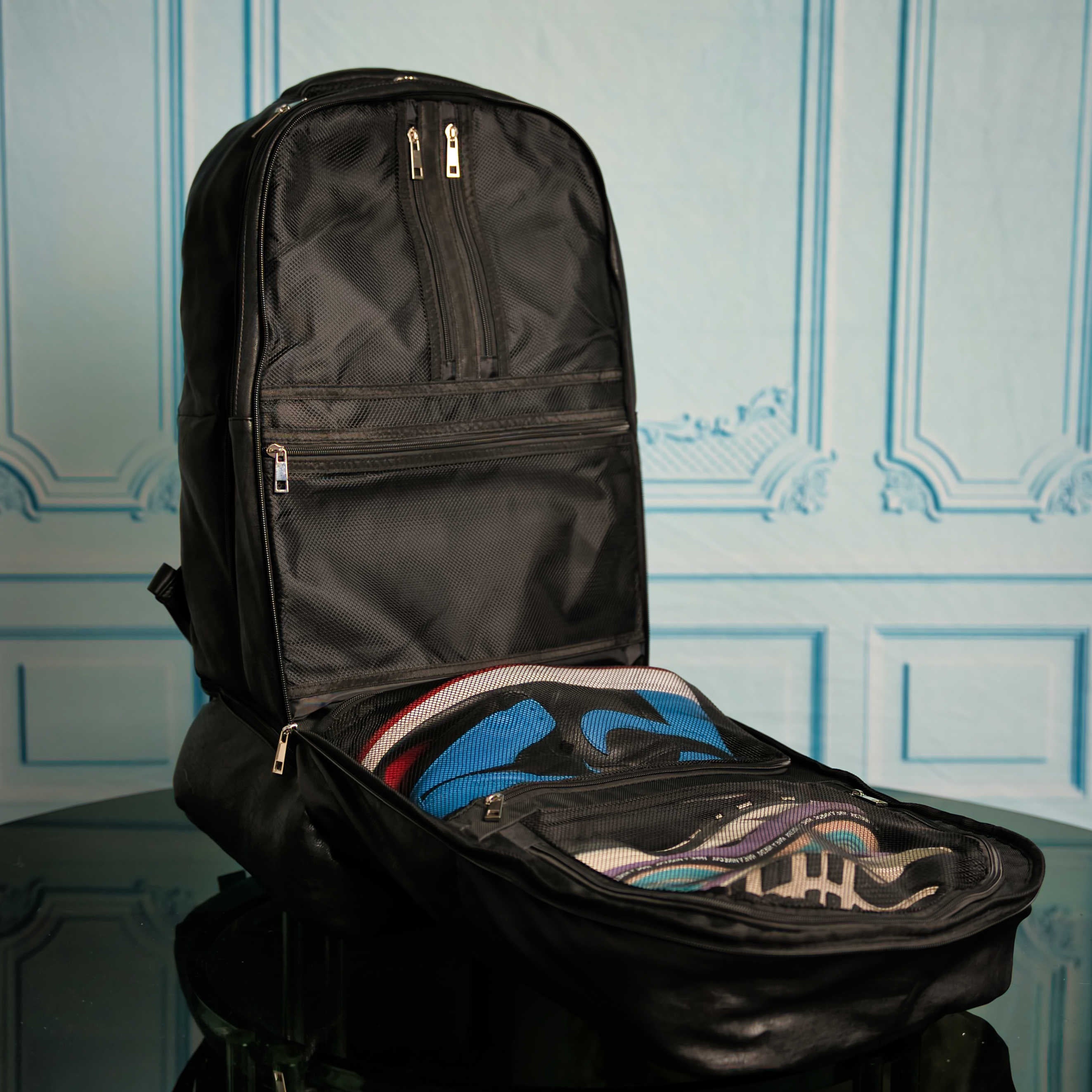 Black backpack with open front compartment showing colorful interior lining against a decorative blue wall.