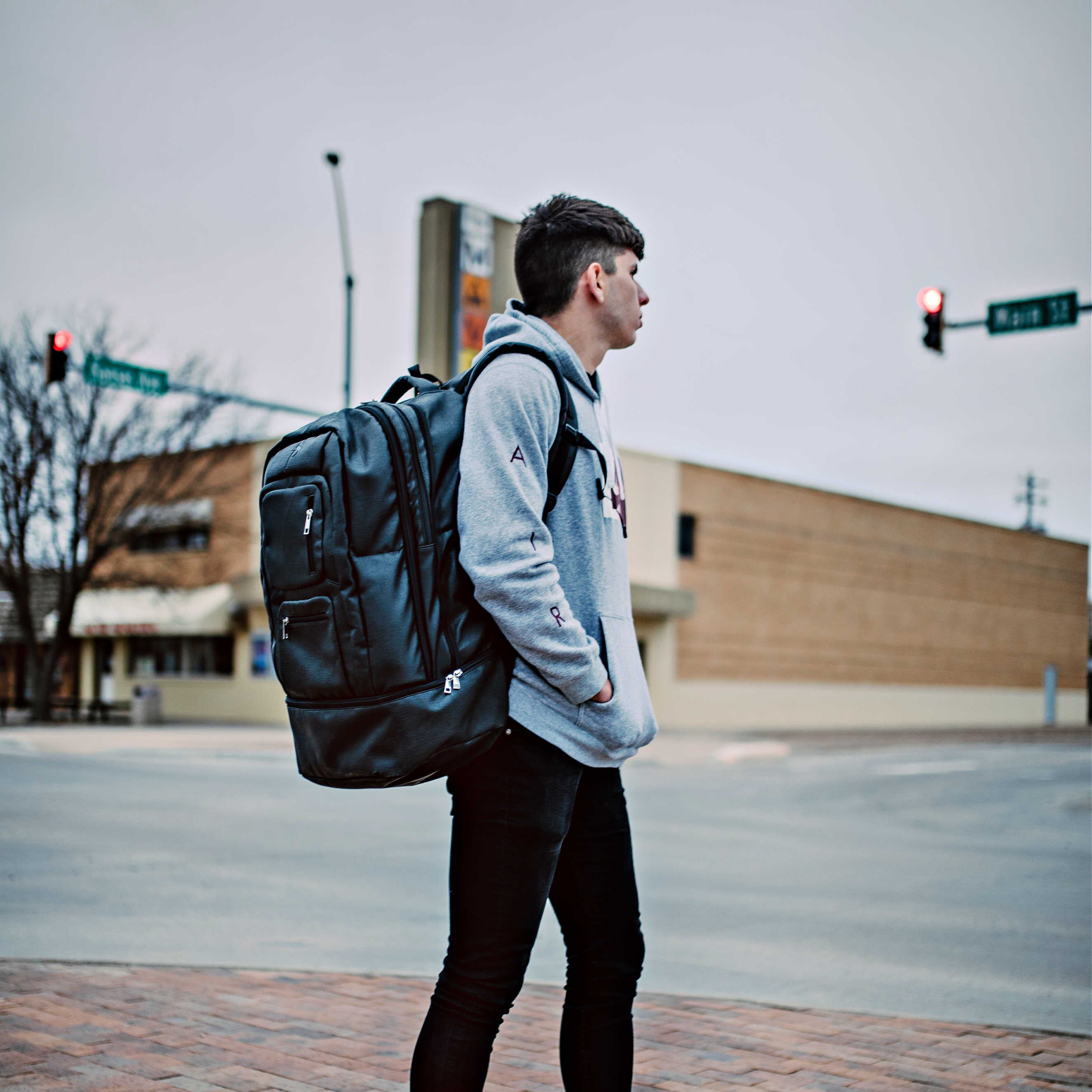 Person with a black backpack standing on a street corner