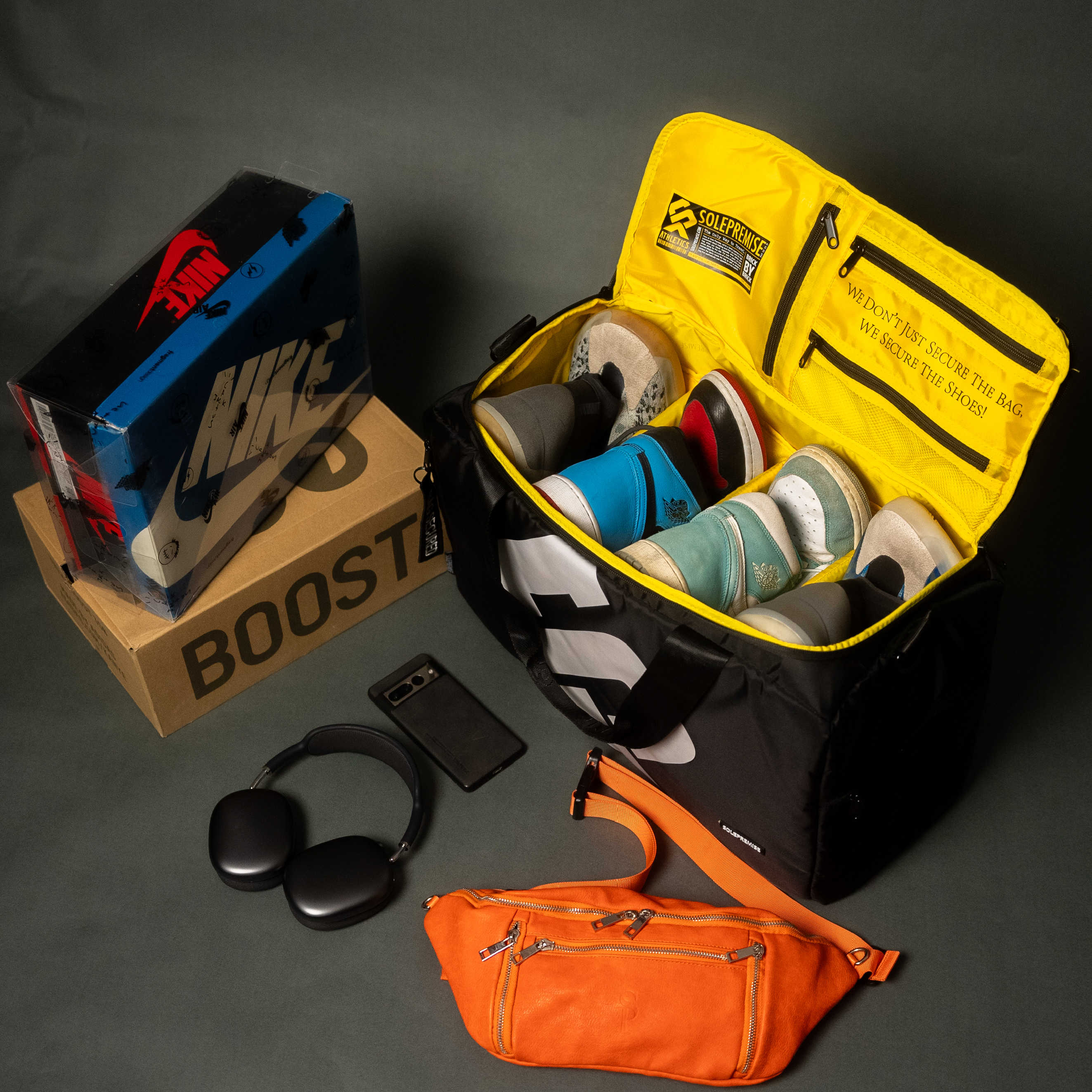Open yellow bag with shoes, Nike box, phone, and orange bag on a dark surface
