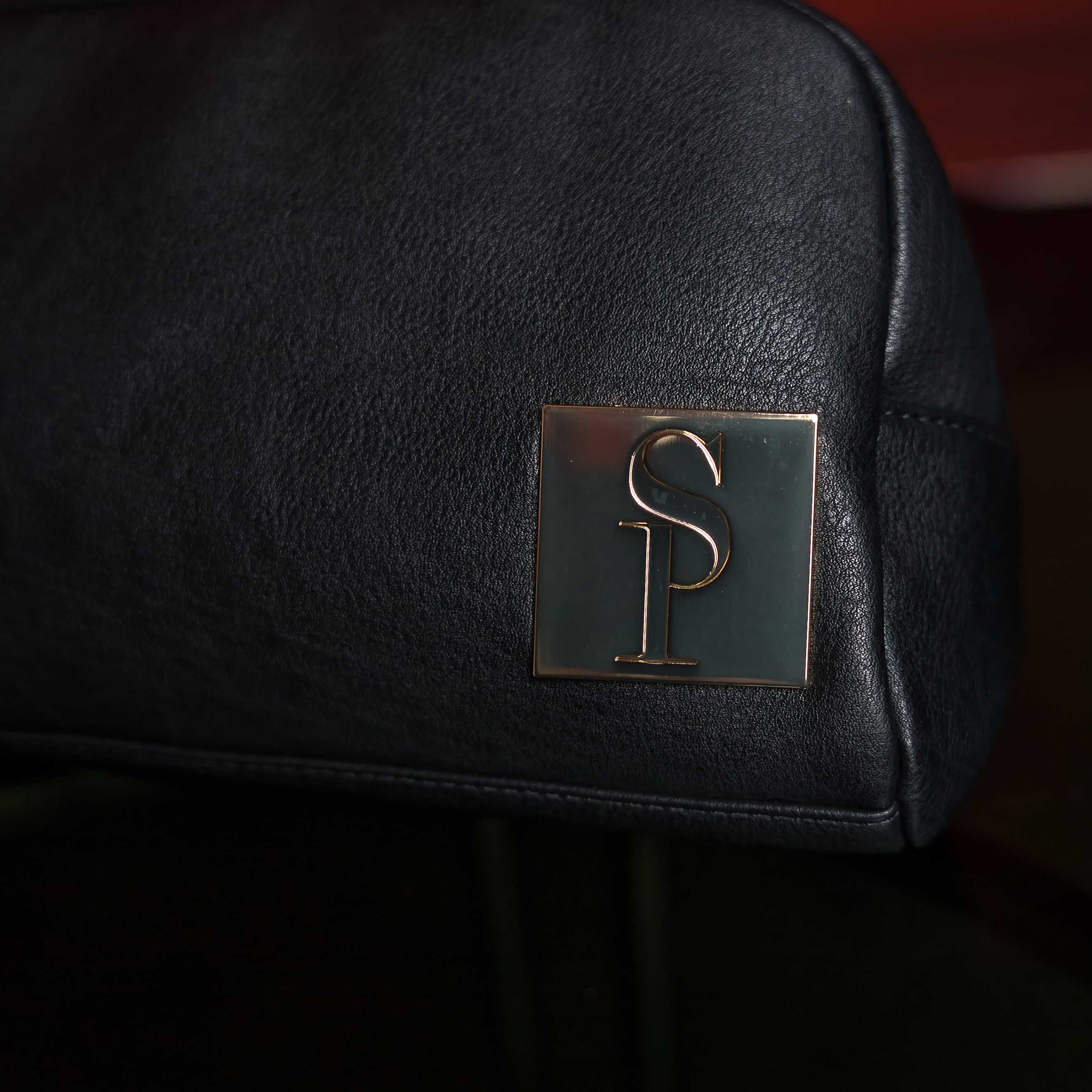 Black leather bag with a gold logo on a dark background