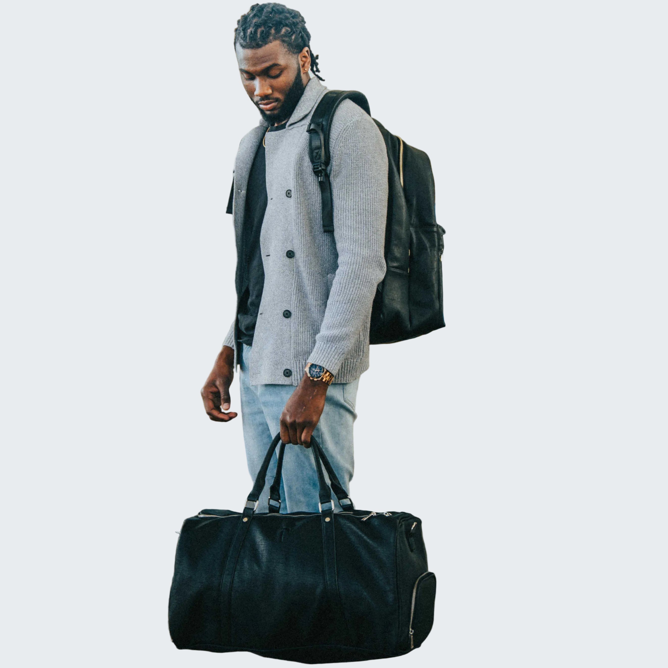 Man with a black duffel bag and backpack walking through an airport terminal.