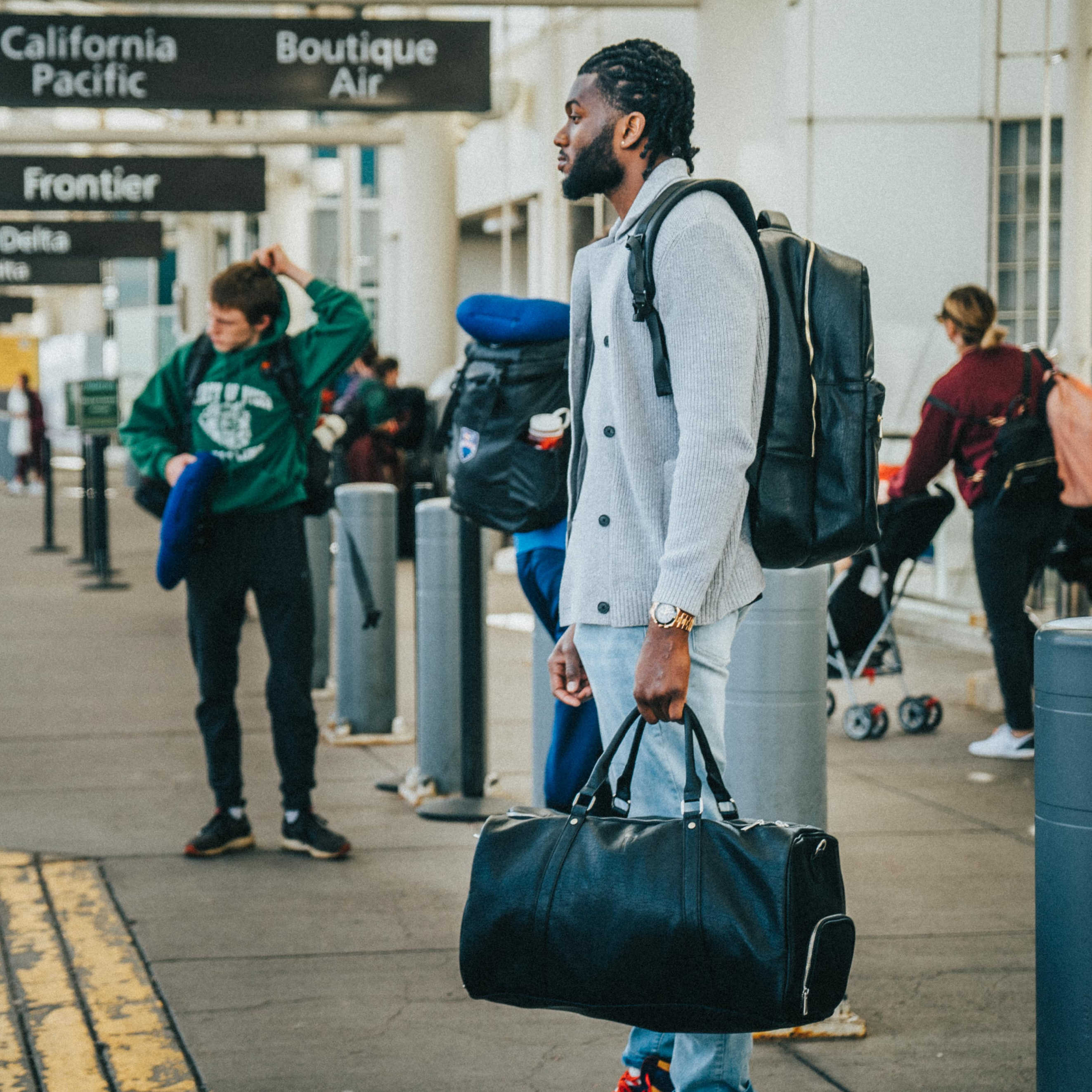 Man with a black duffel bag walking through an airport terminal.