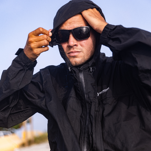 Man wearing a black jacket and sunglasses with a blurred background