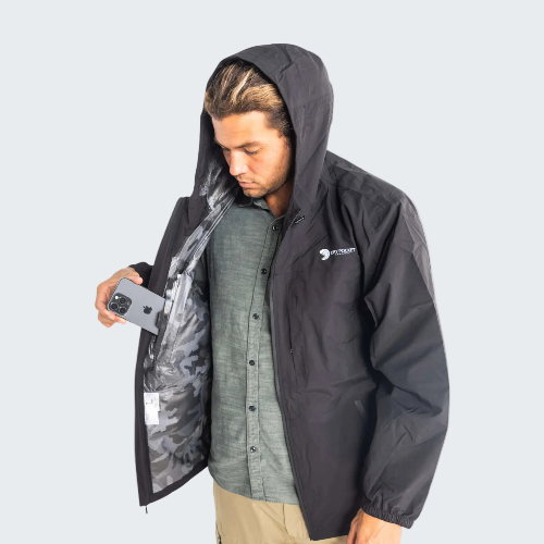 Person wearing a black raincoat with a hood, holding a phone.