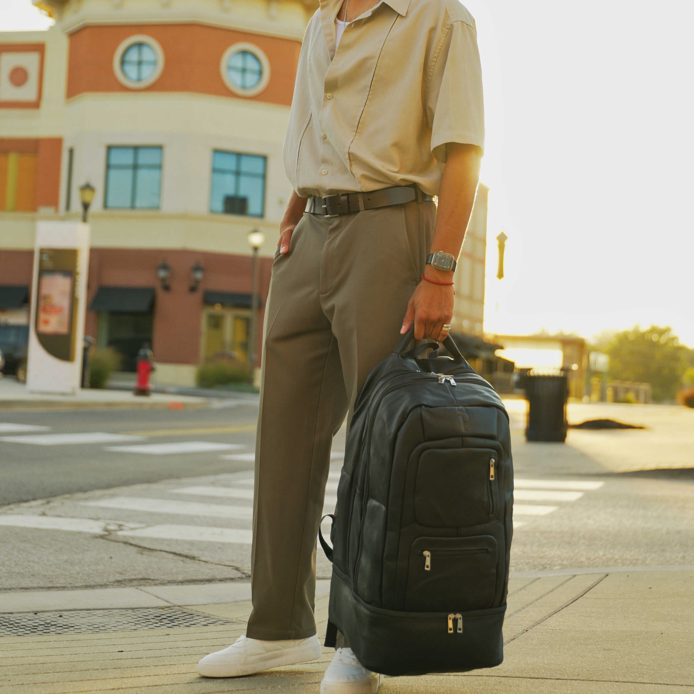 Person holding a black backpack on a city street with a building in the background
