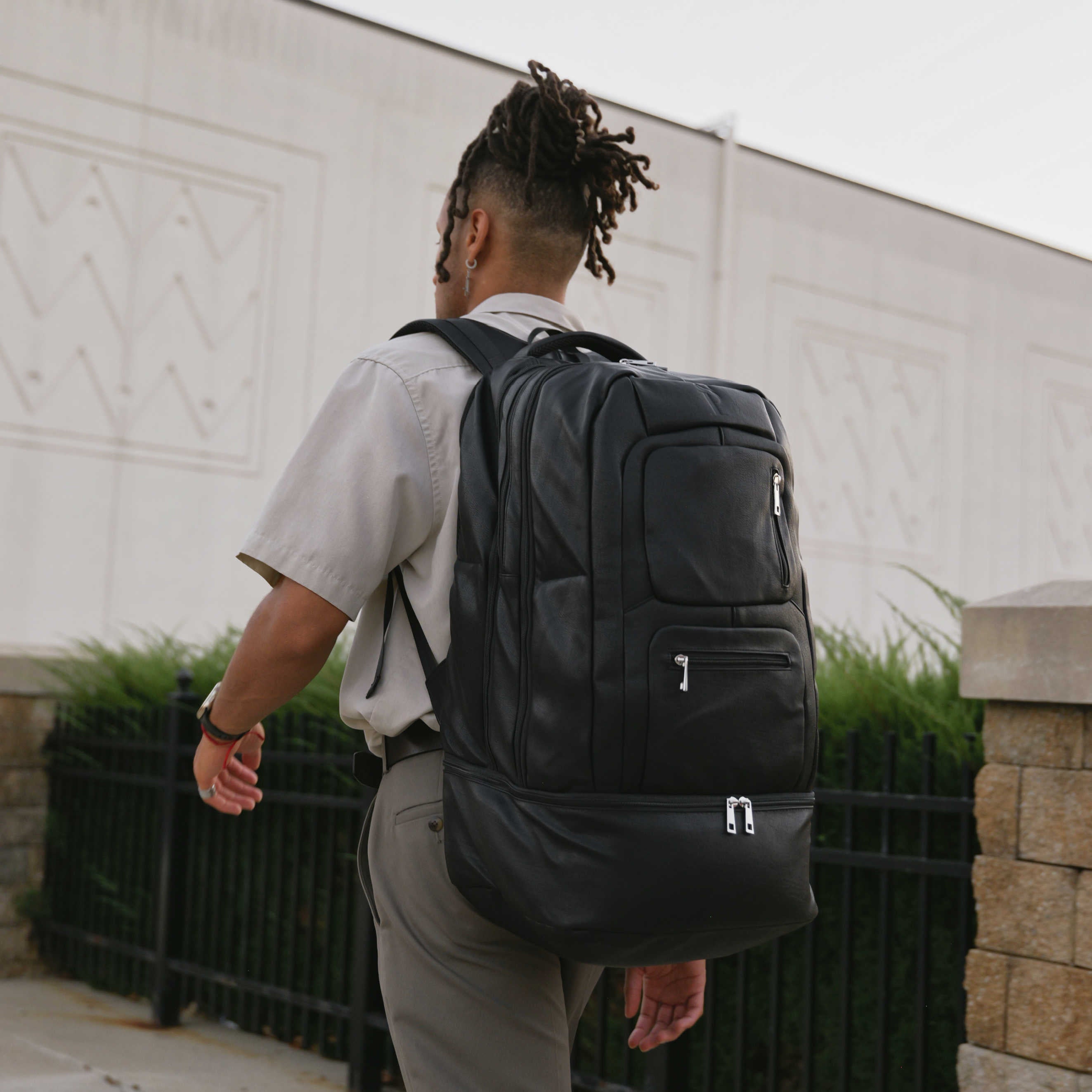 Person wearing a black backpack outdoors with a neutral background