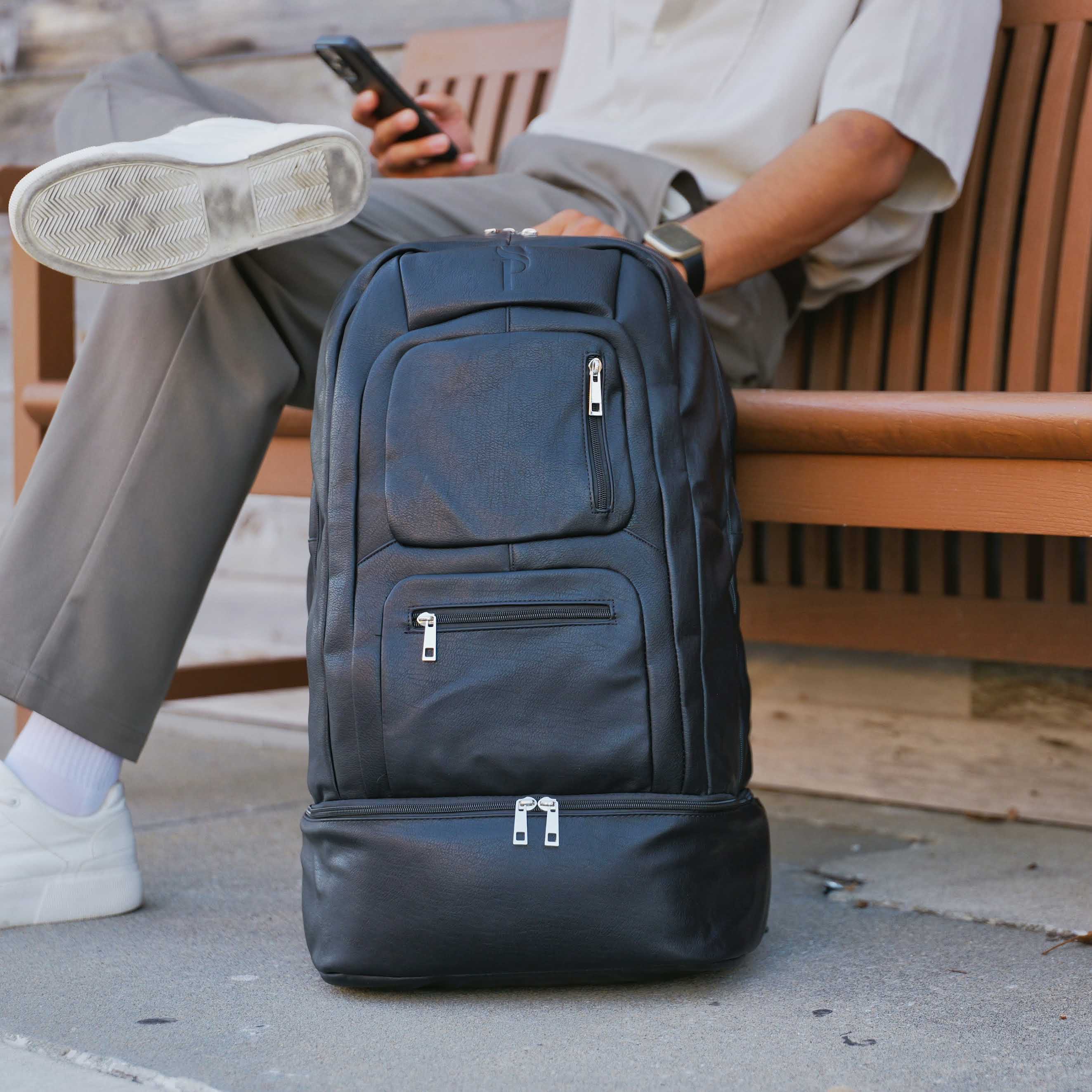 Person sitting on a bench with a large black backpack in front of them.