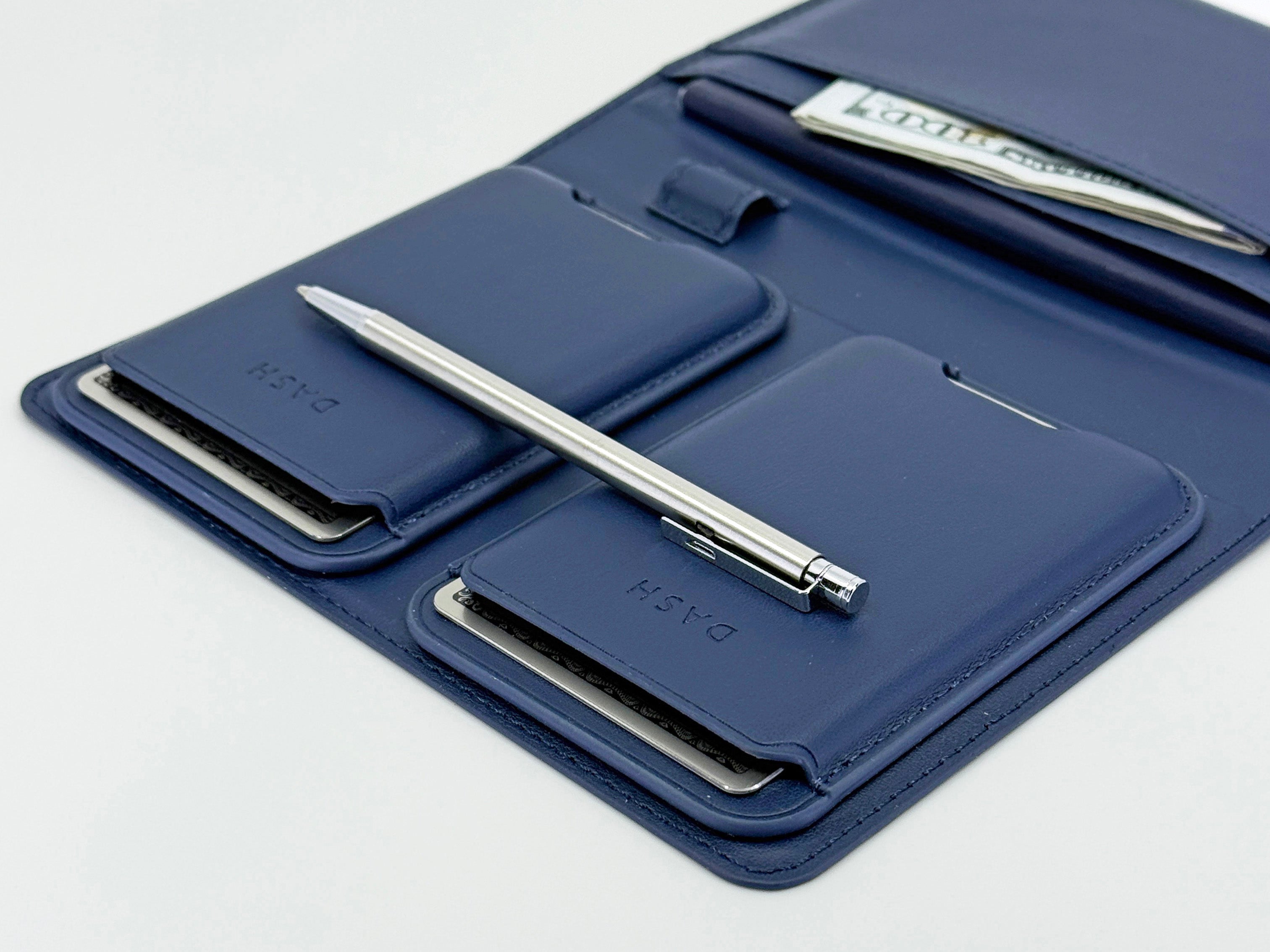 Blue leather notebook with pen holder and pens on a light gray background