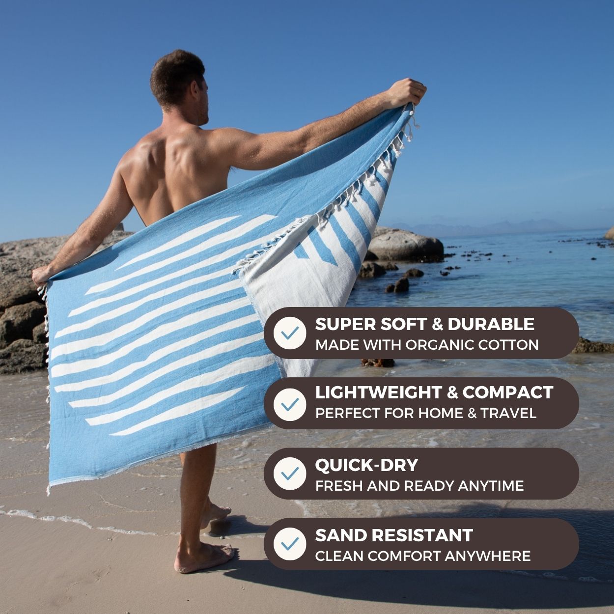 Man holding a blue and white striped towel on a beach with product features displayed.