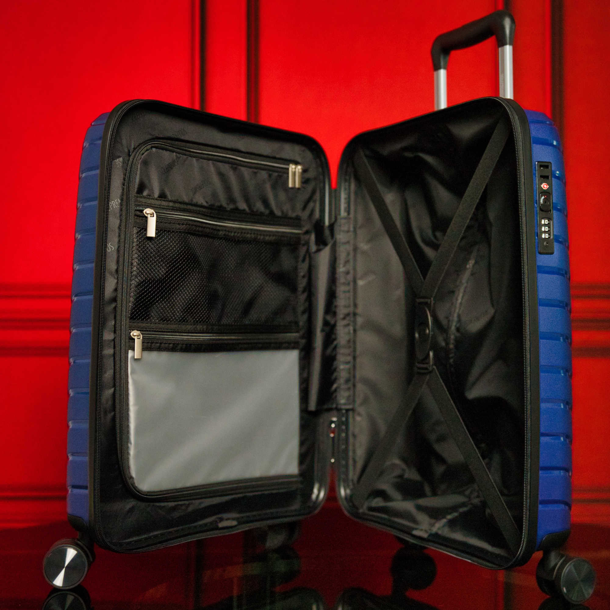 Open blue suitcase with black interior against a red background