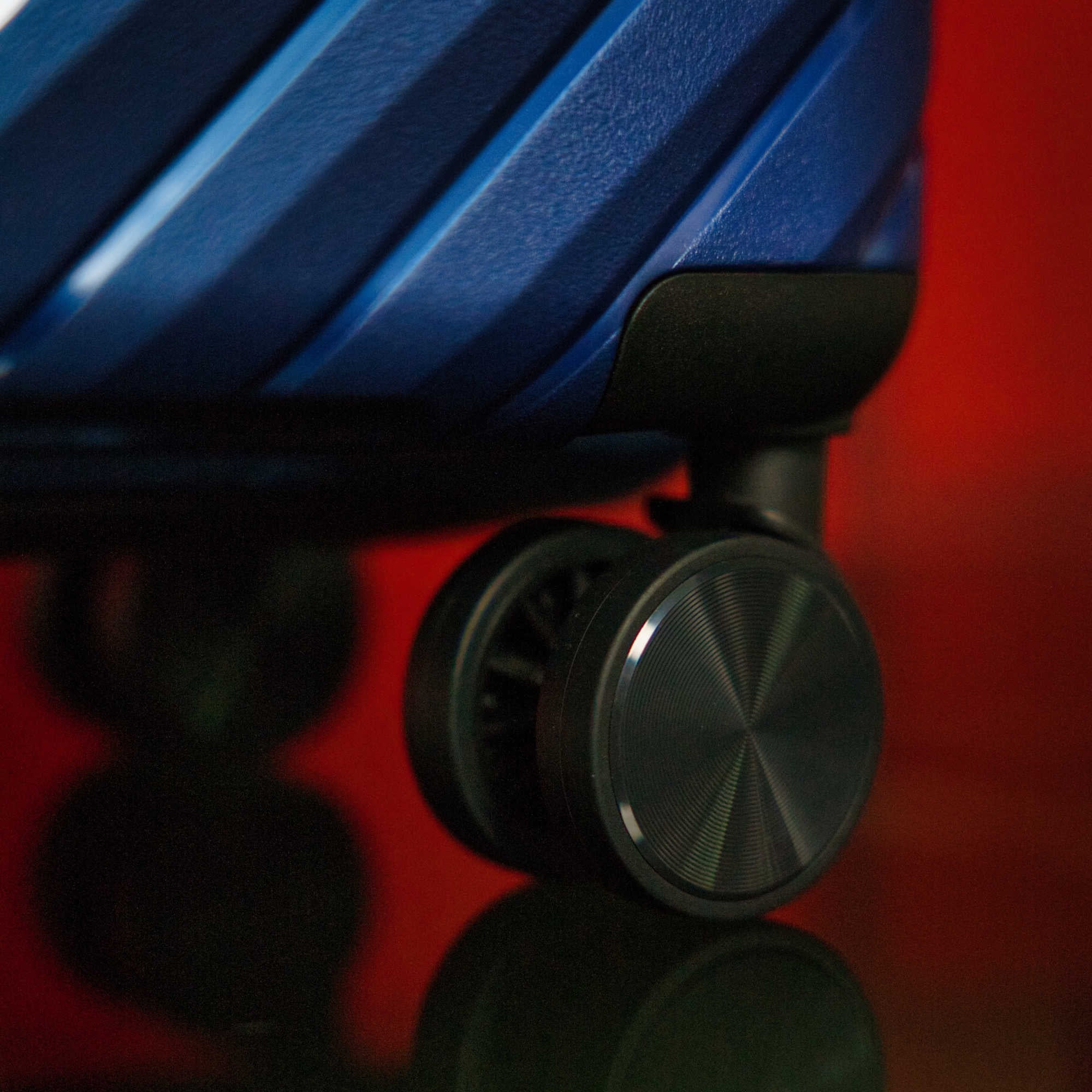 Close-up of a blue suitcase with a black handle on a red background
