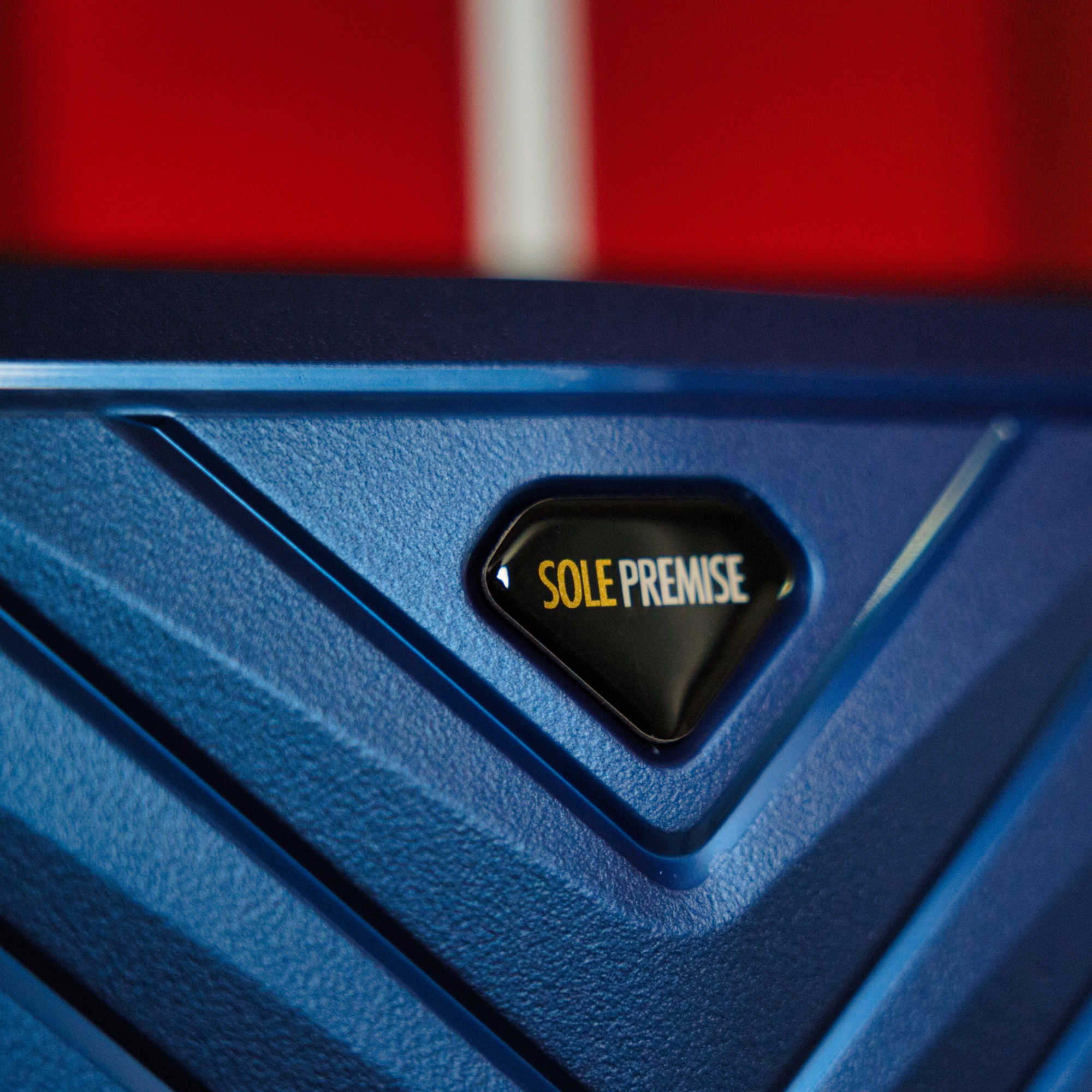 Blue suitcase with 'SOLE PREMISE' logo on a red background