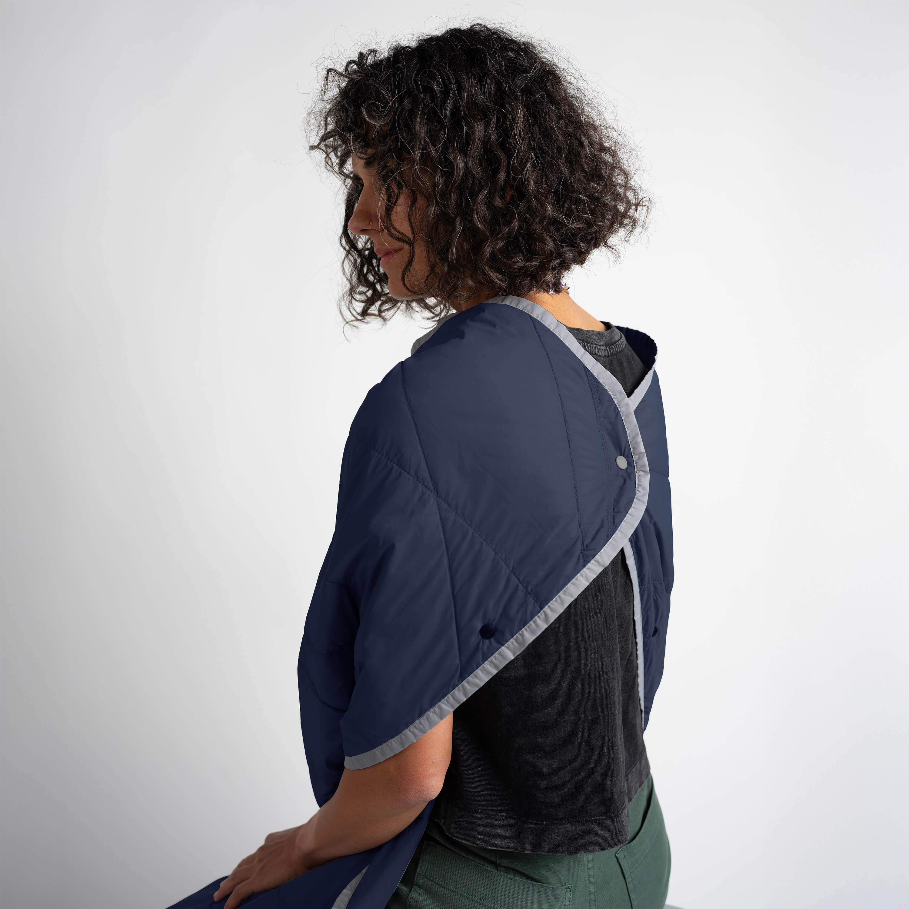 Person wearing a navy blue jacket with gray trim on a white background