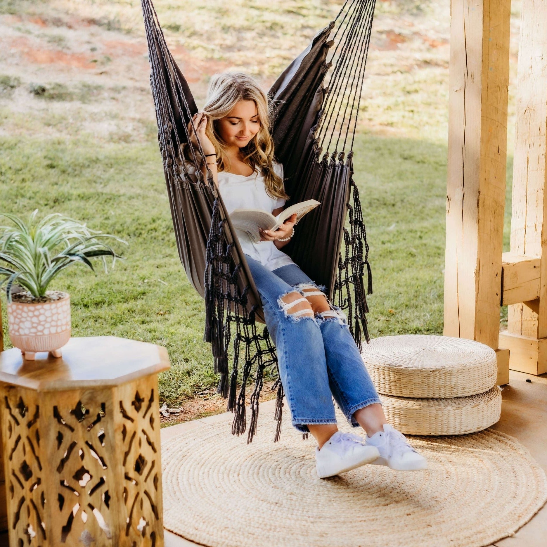 Woman reading a book in a black hammock outdoors