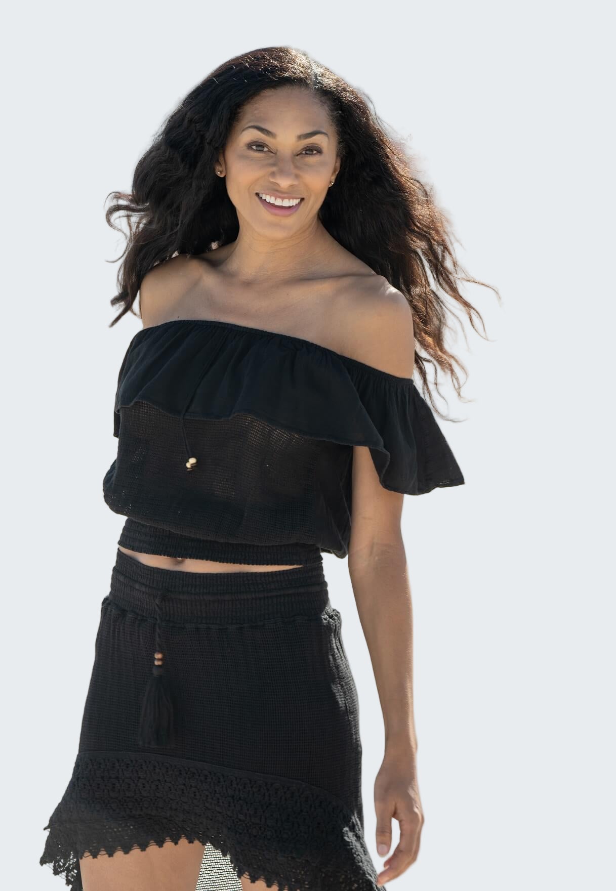 Woman wearing a black off-shoulder top and skirt on a blurred outdoor background