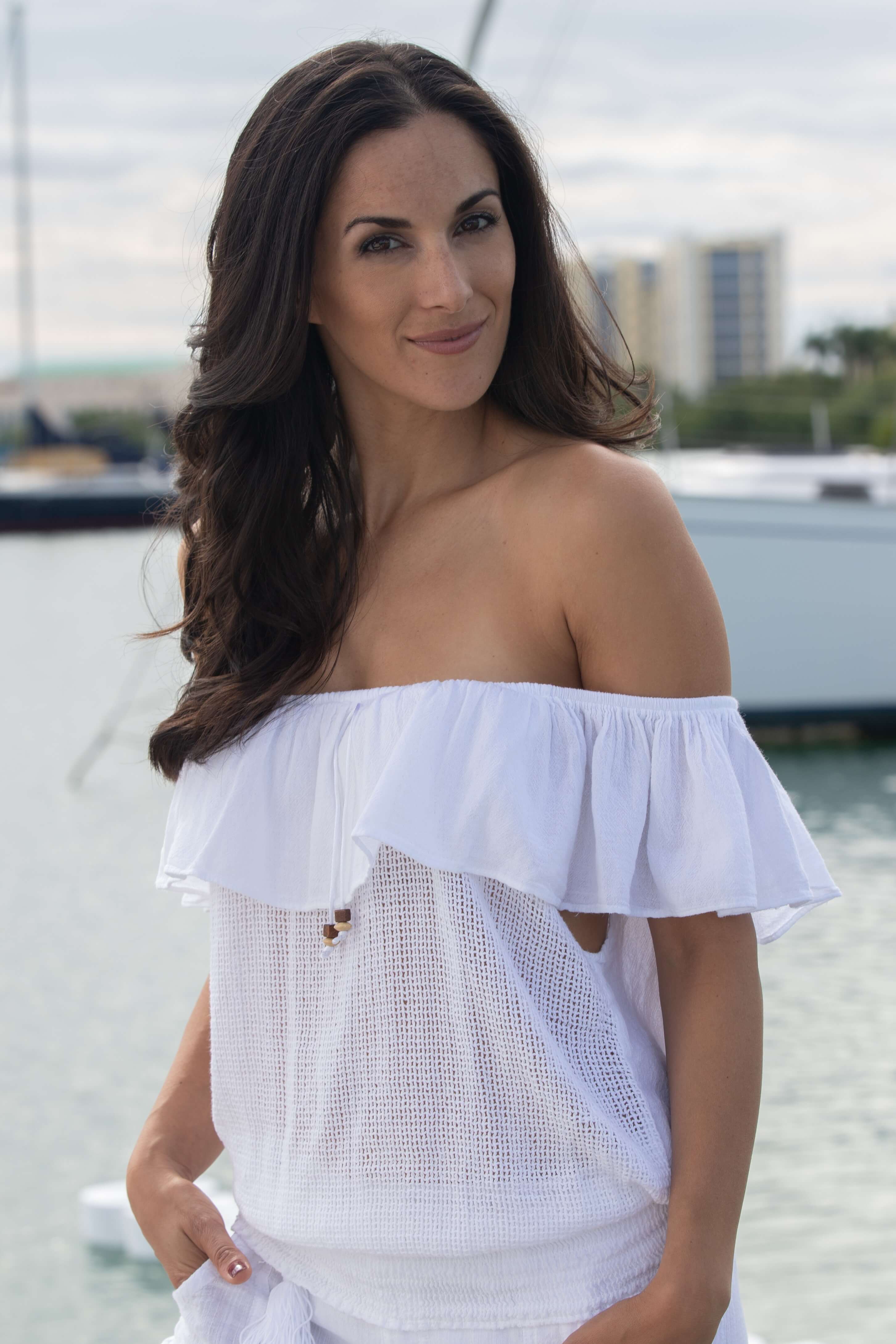 Woman wearing a white off-shoulder top with a blurred background