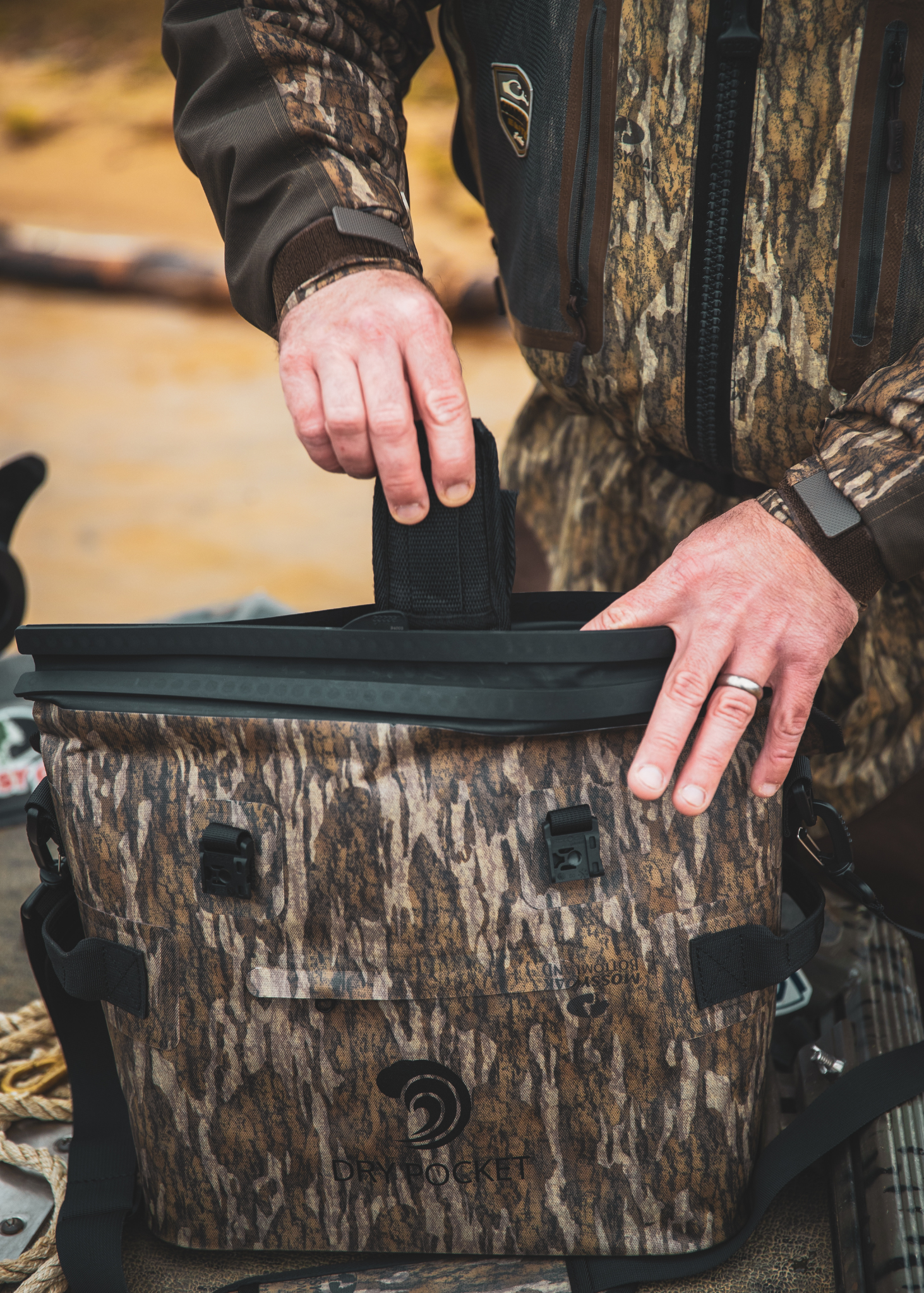 Person in camouflage clothing opening a camo-patterned cooler.