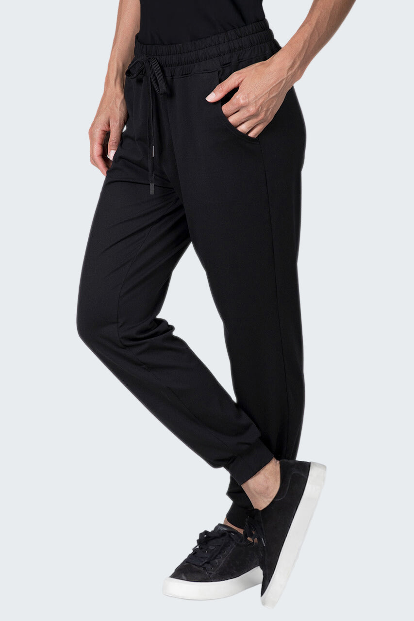 Person wearing black jogger pants and black sneakers on a white background