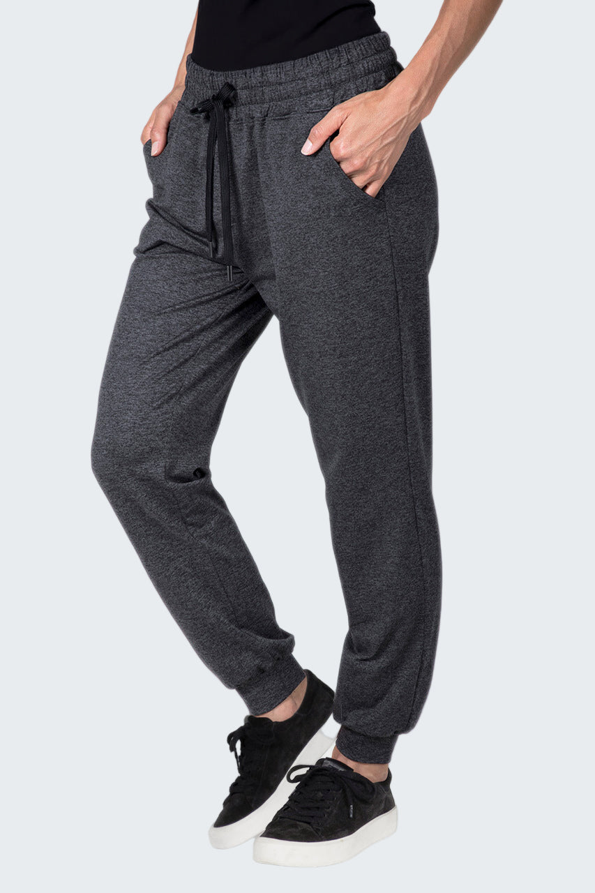 Person wearing gray jogger pants and black sneakers on a white background