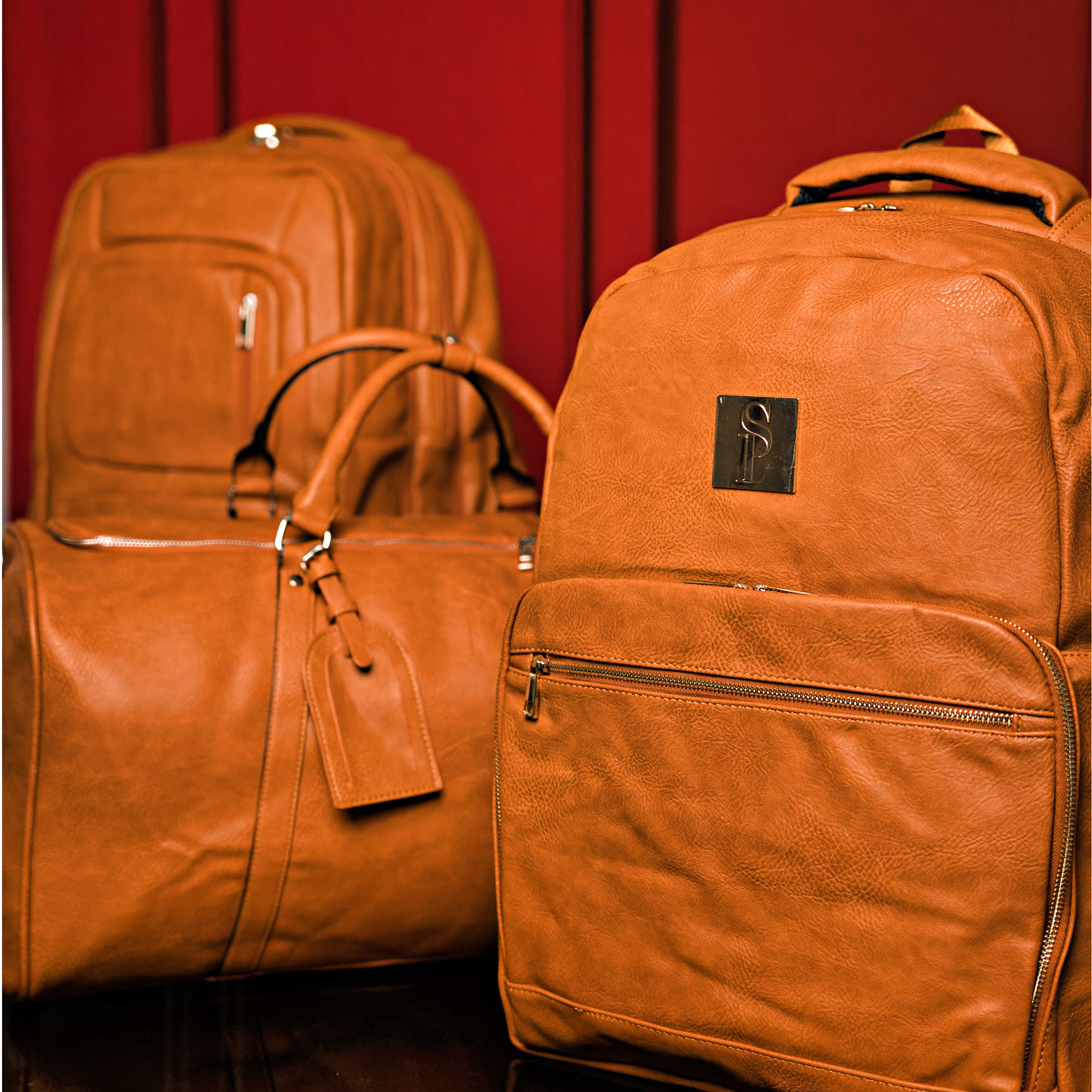 Three brown leather bags with a visible brand logo against a red background