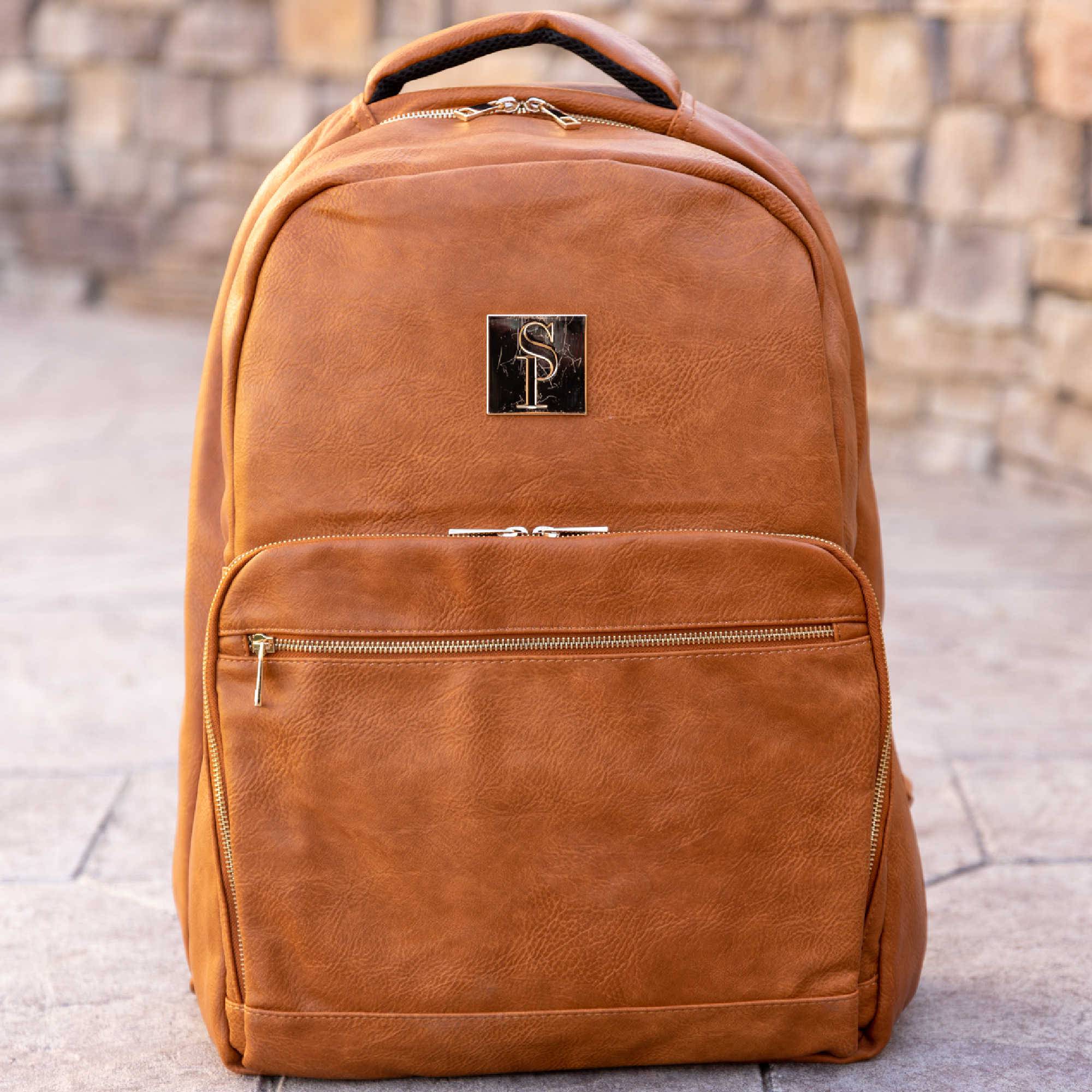 Brown leather backpack with a brand logo on a stone pavement background