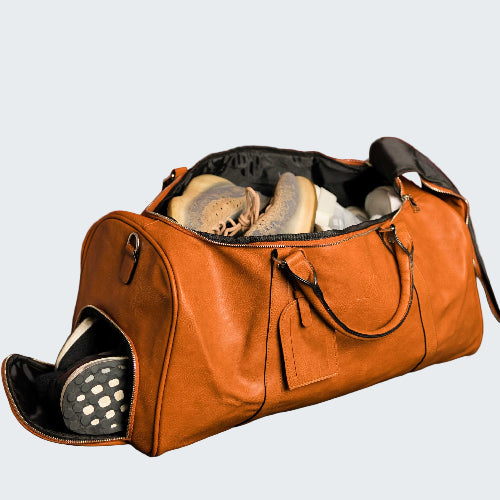 Brown leather duffel bag with shoes against a red paneled wall