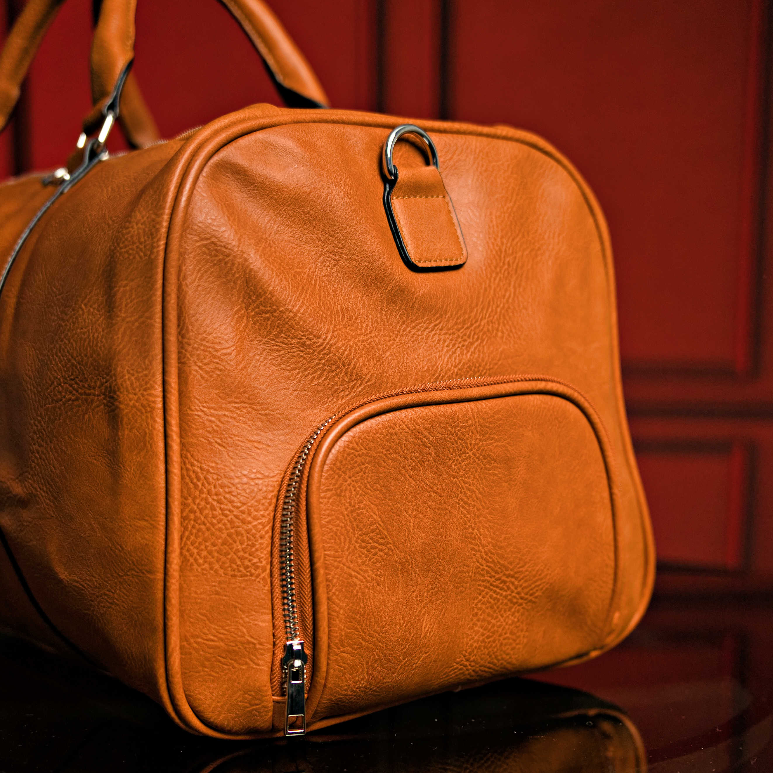 Brown leather bag with a zipper on a red background