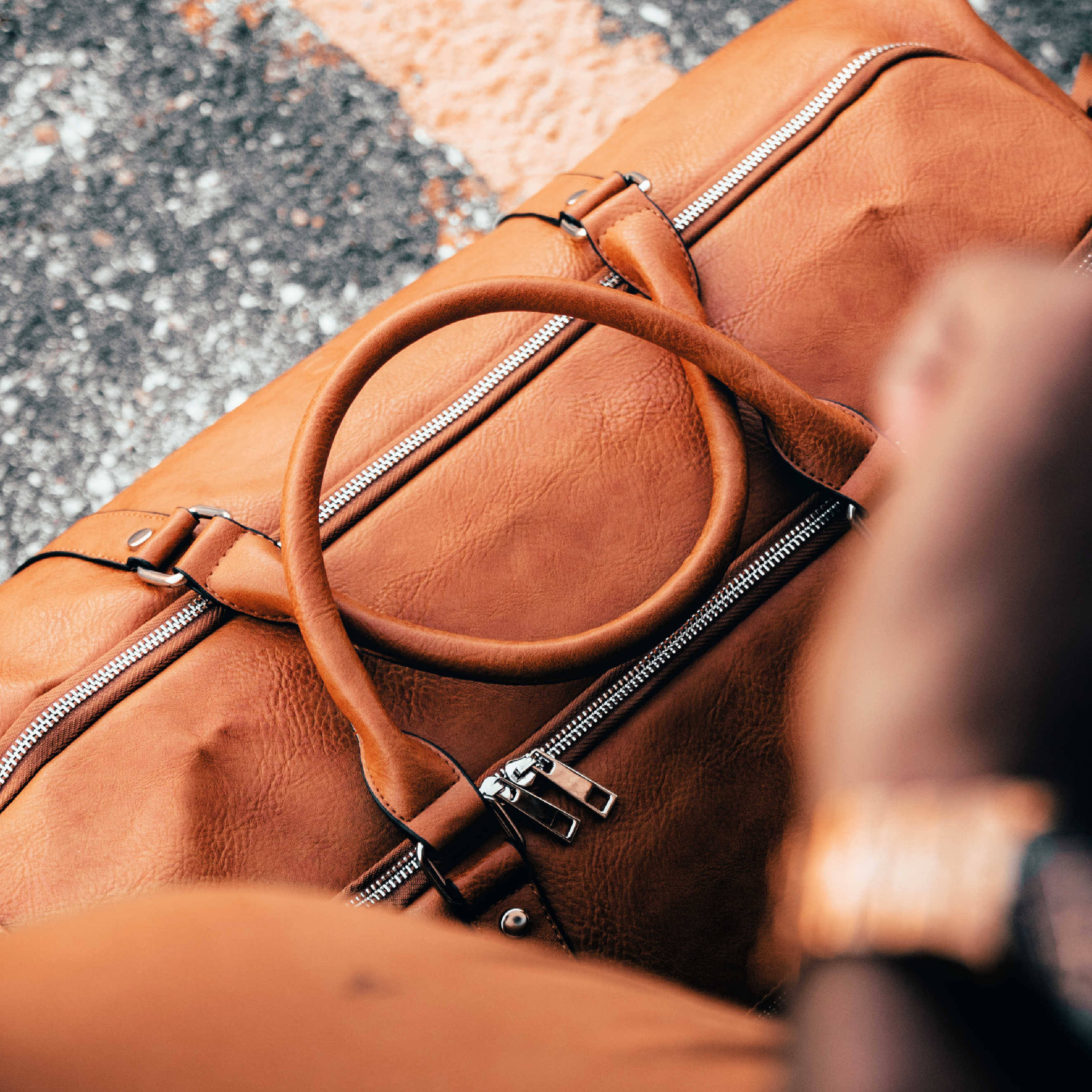 Brown leather duffel bag on a textured surface