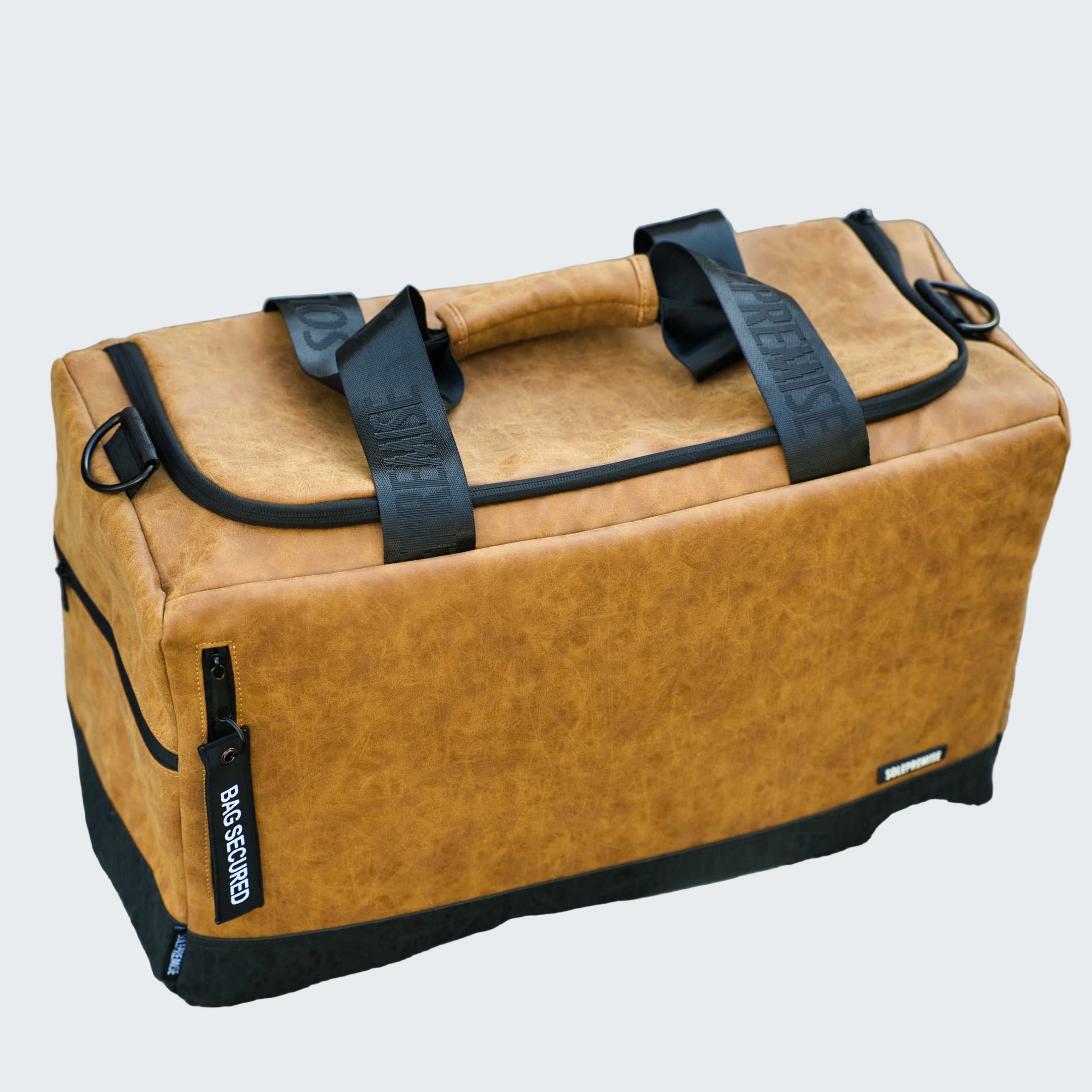 Brown leather bag with black straps on a road surface