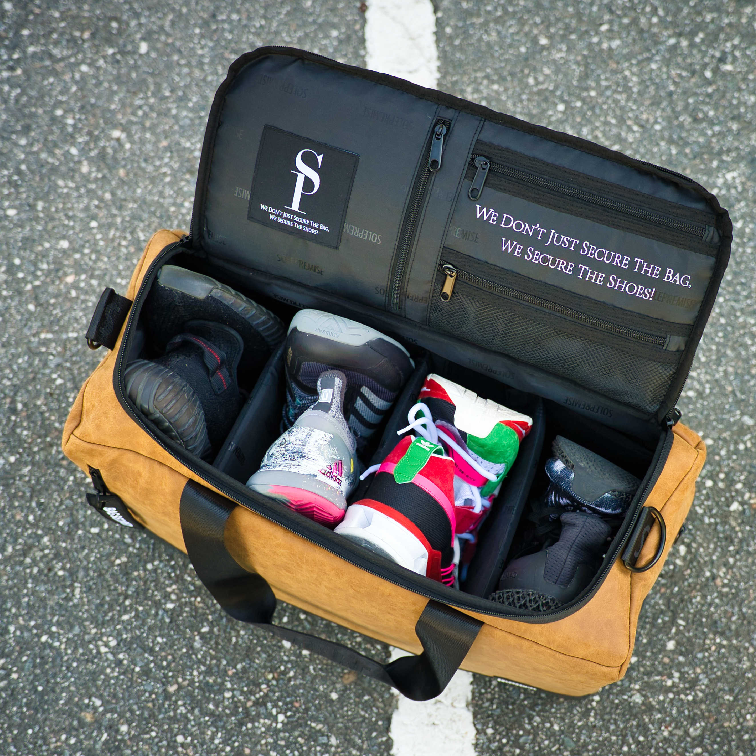 Brown duffel bag with black interior compartment containing shoes on a gray pavement background.