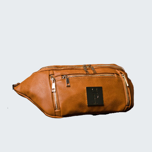 Brown leather bag with gold zippers on a red reflective surface