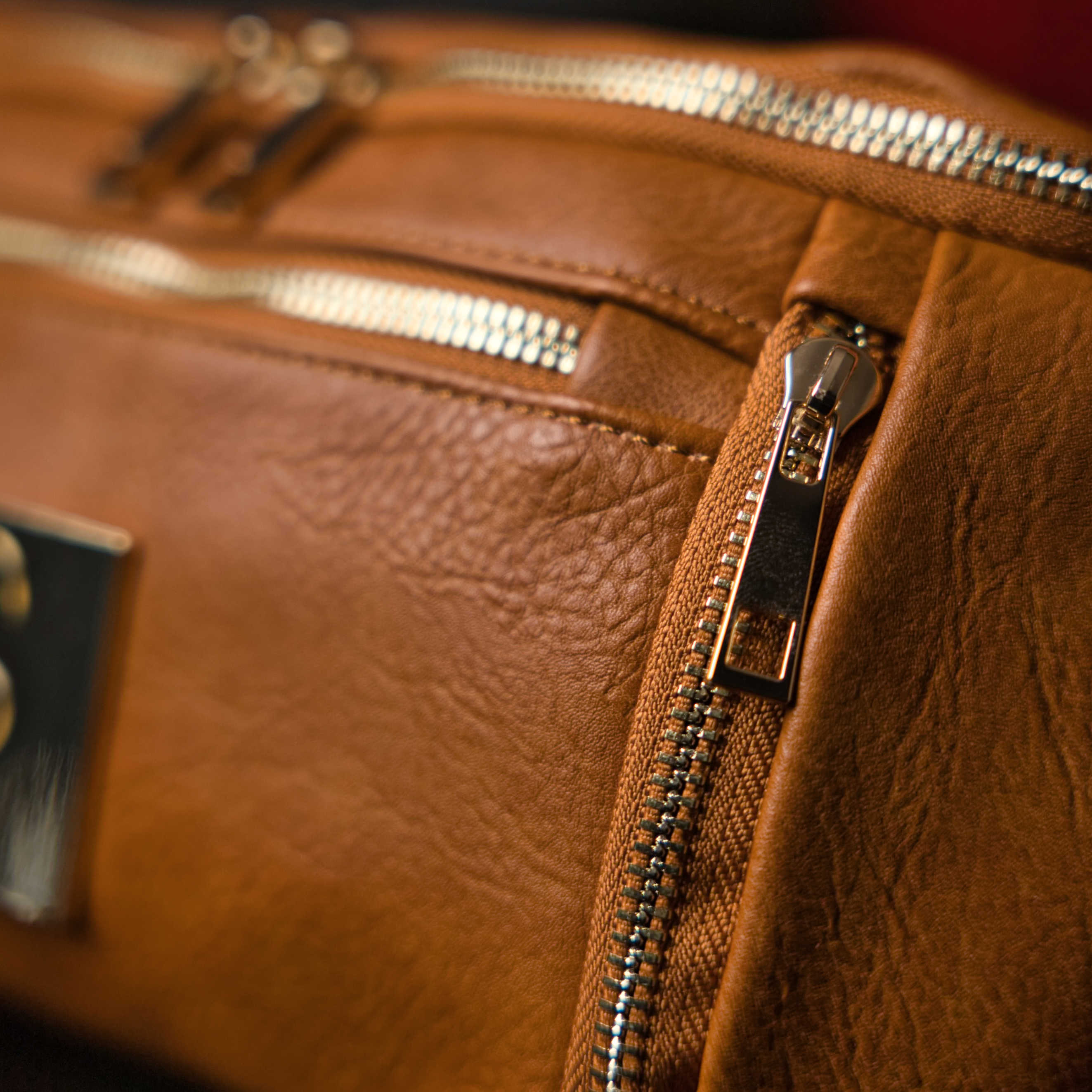 Close-up of a brown leather bag with zippers