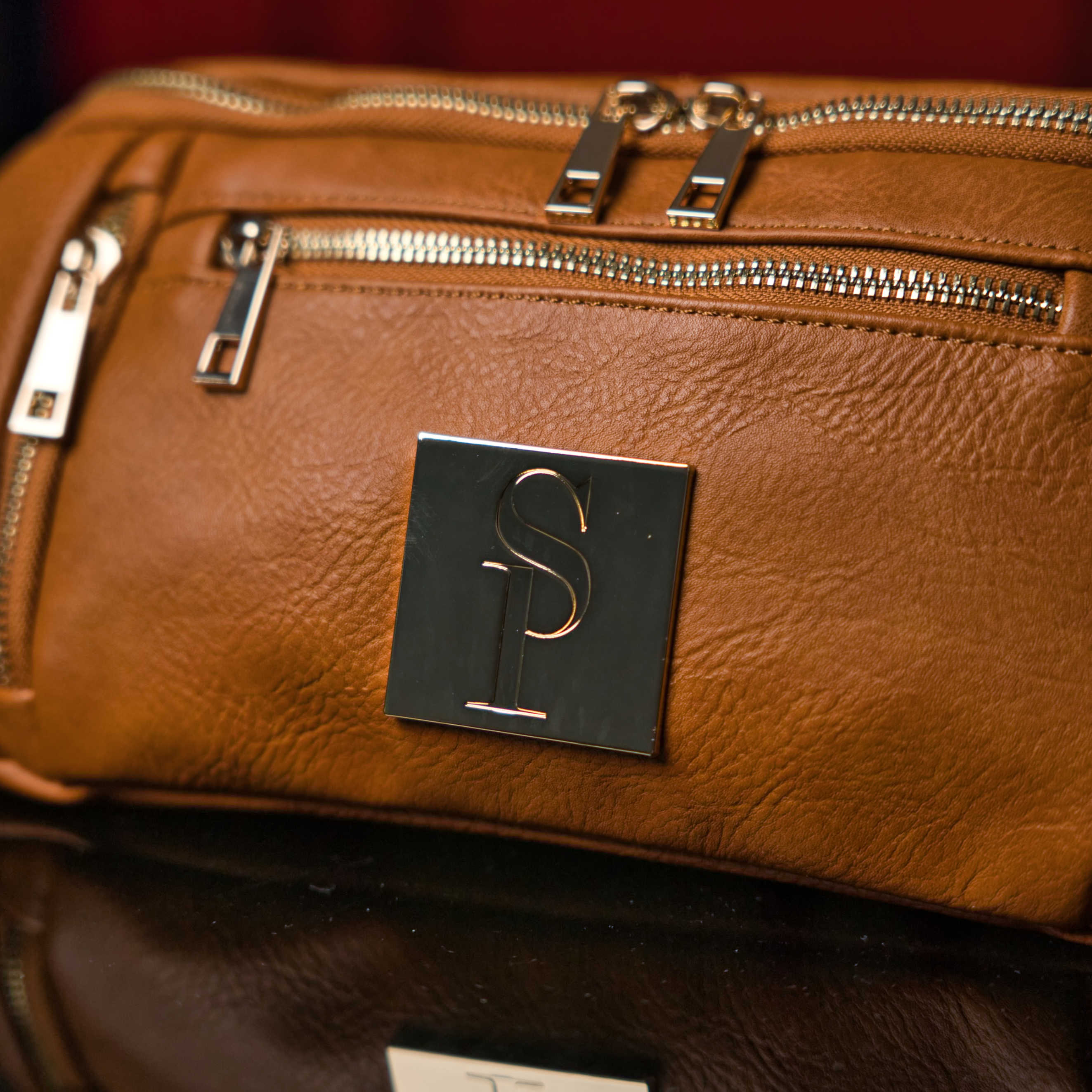Brown leather bag with a logo on a dark background