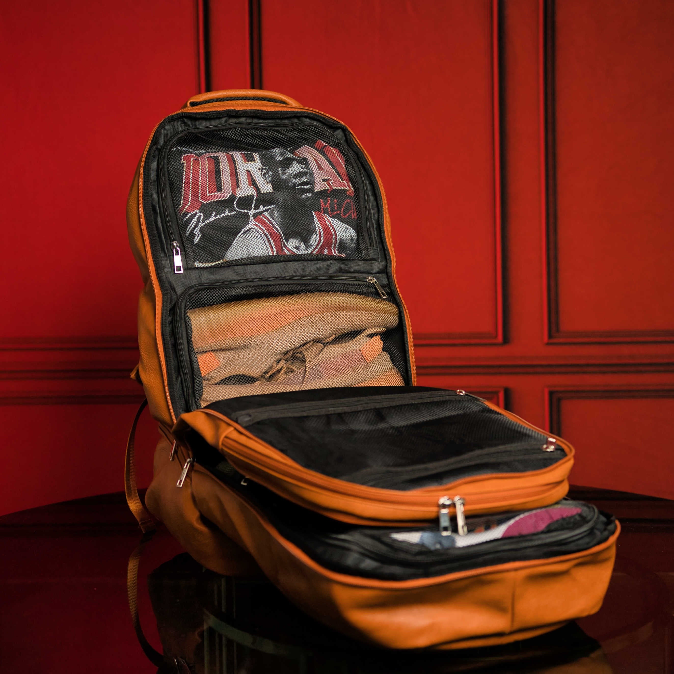Orange backpack with a clear front pocket on a red background