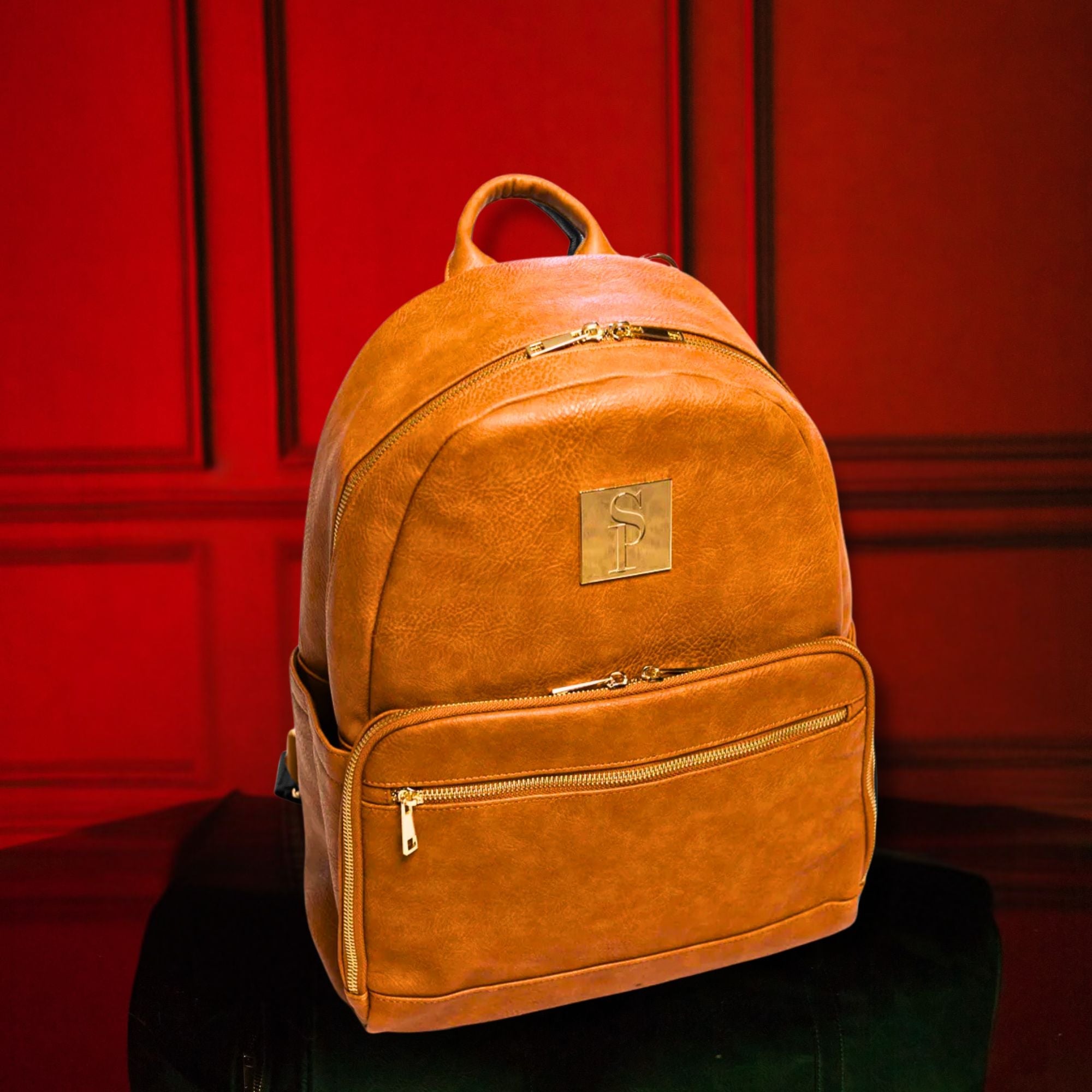 Brown leather backpack with a gold zipper and logo on a red background