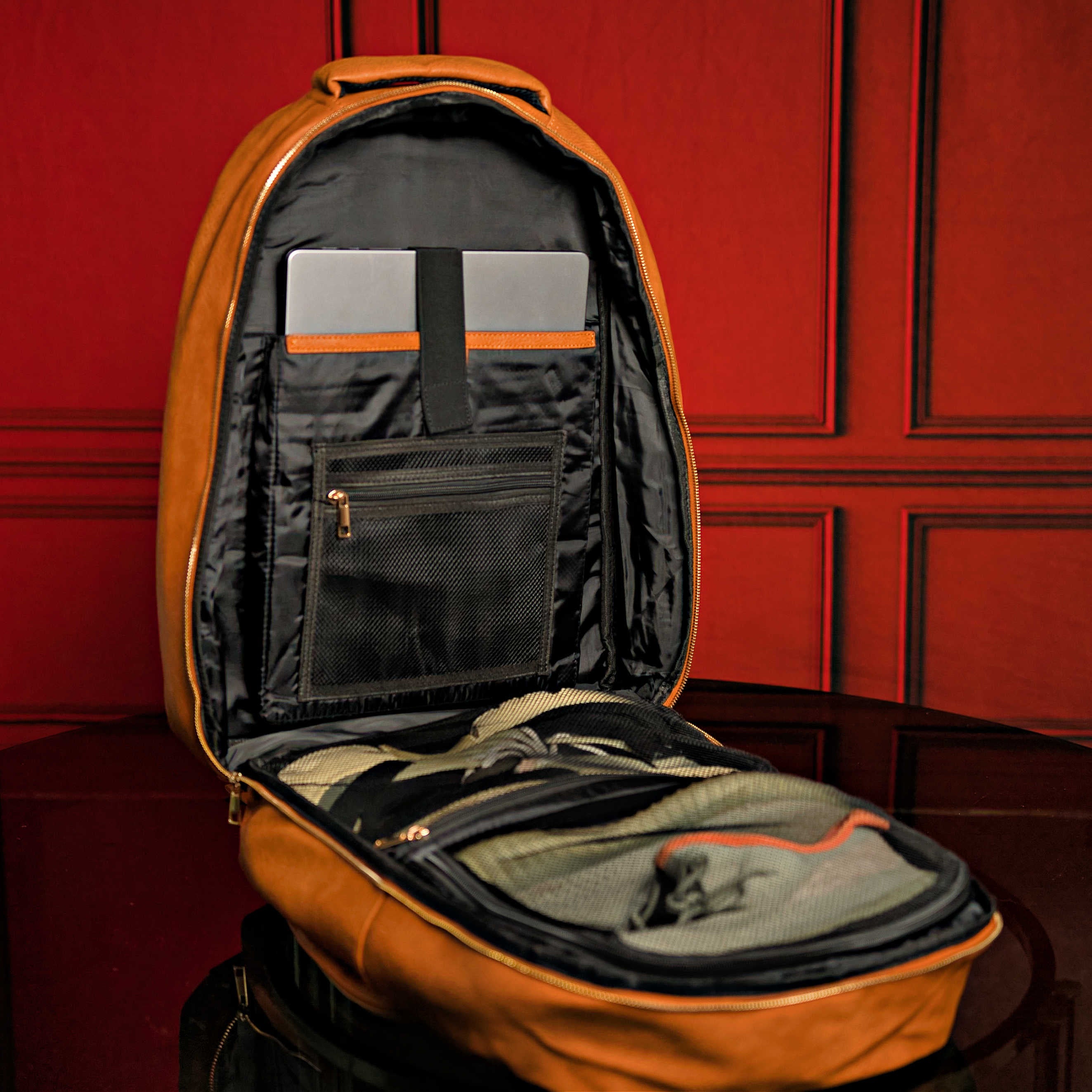 Open brown backpack with compartments against a red paneled wall