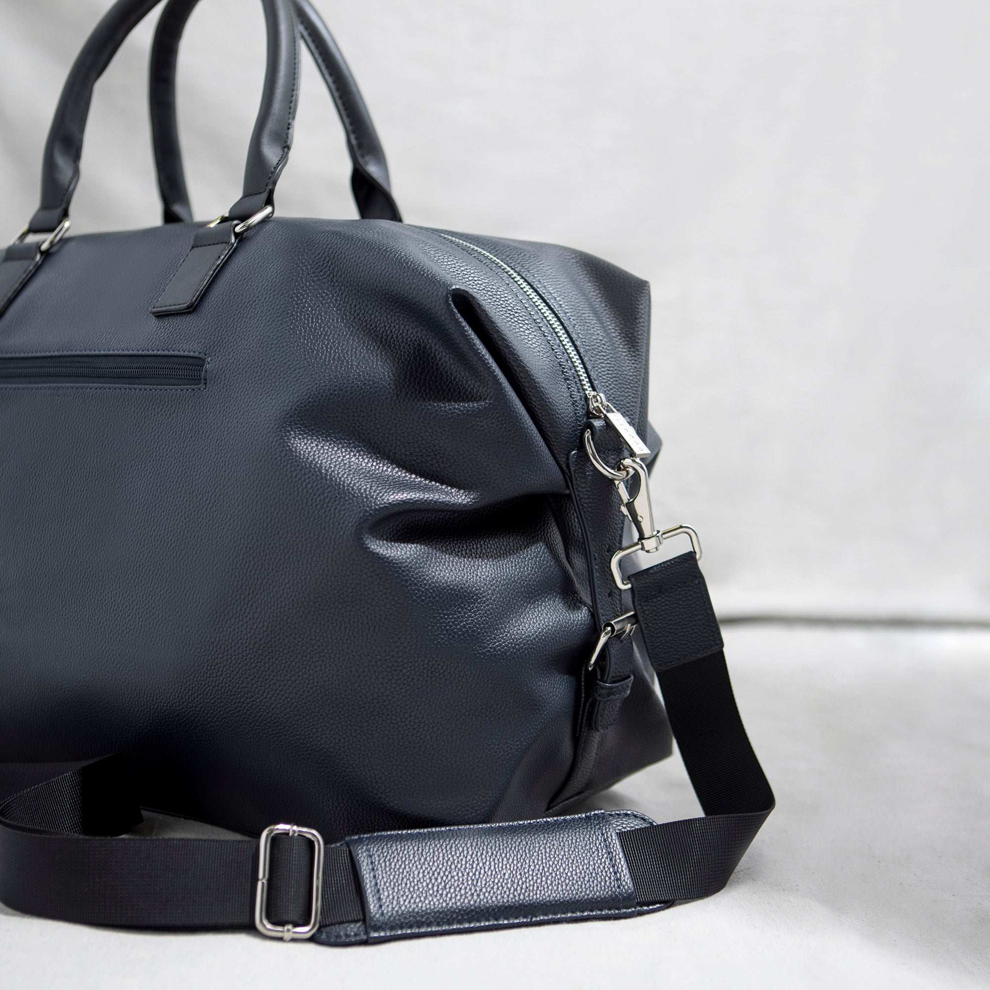 Black duffel bag with a strap on a light gray background